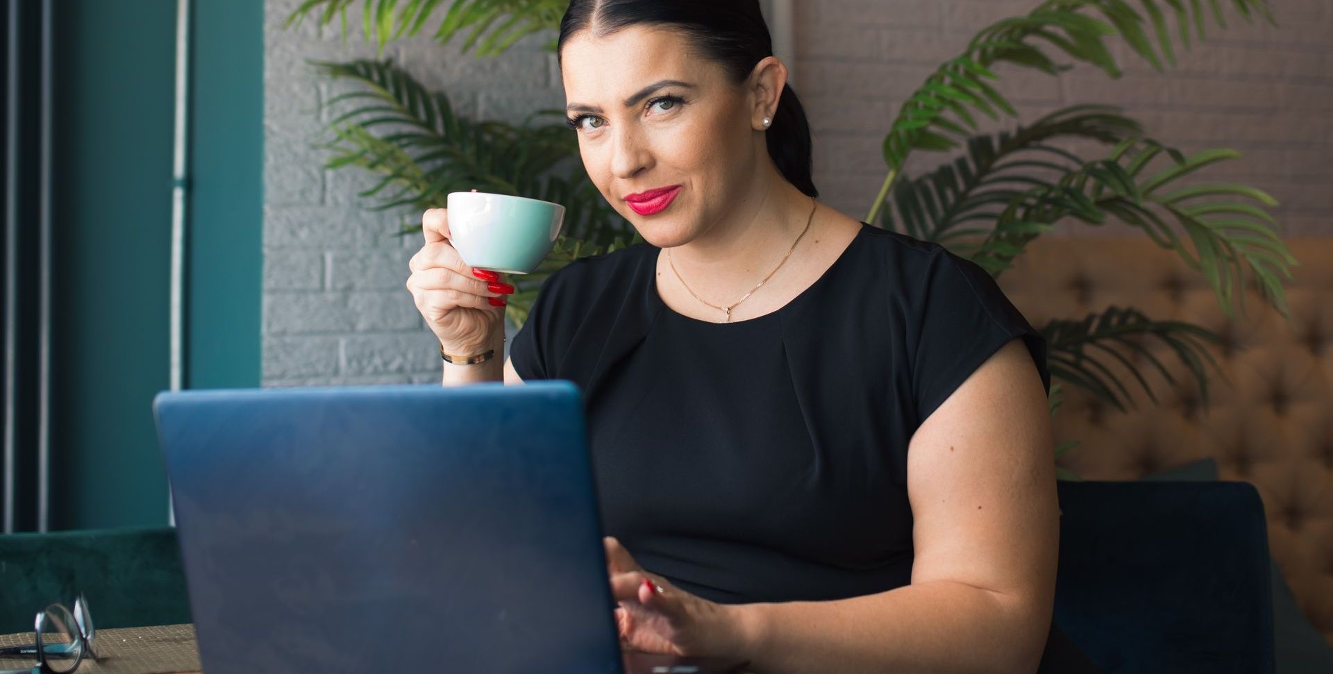 A woman is drinking coffee while using a laptop computer to make revenue blogging.