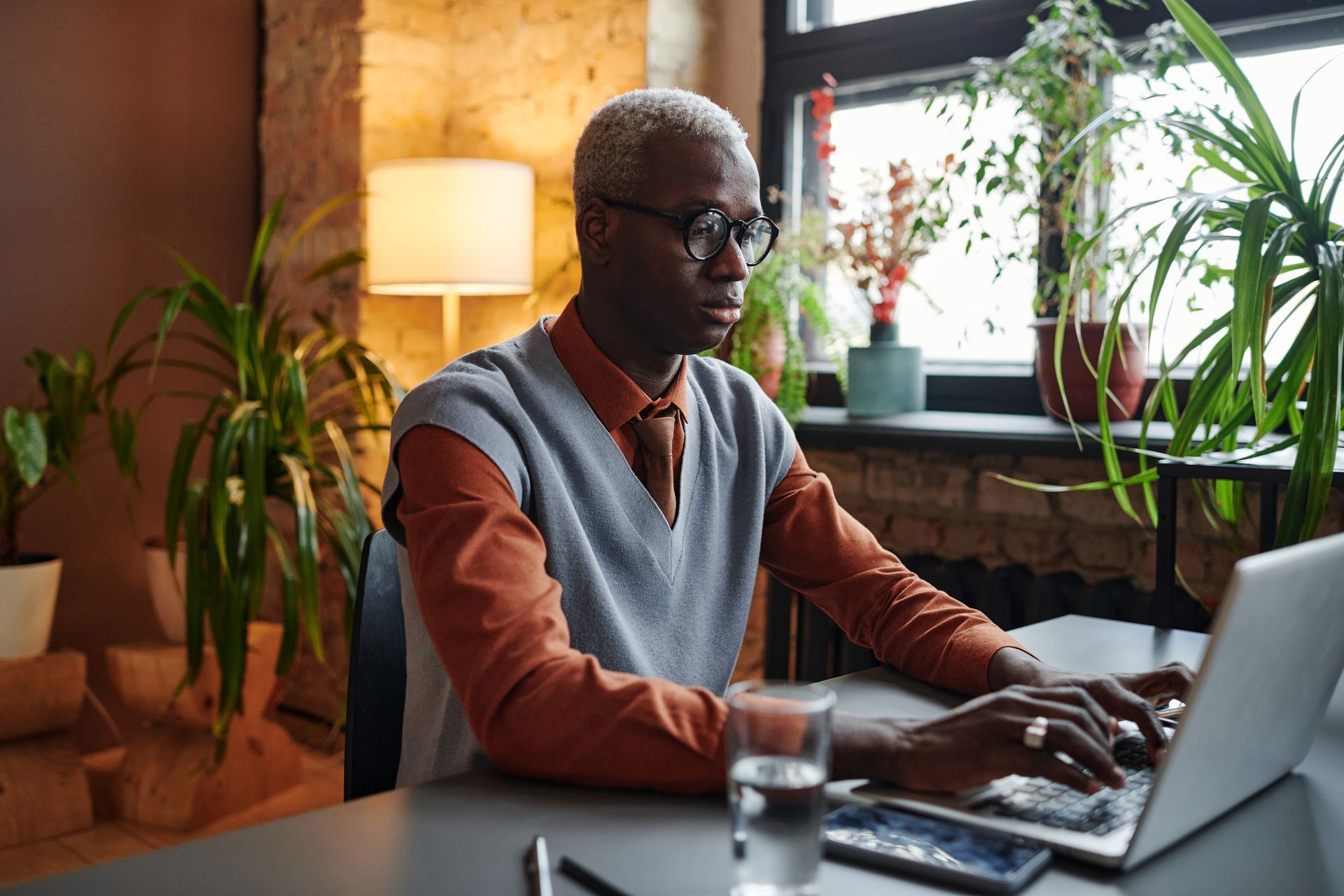 A man is sitting at a desk using a laptop computer to create blog content for his business to generate more revenue.