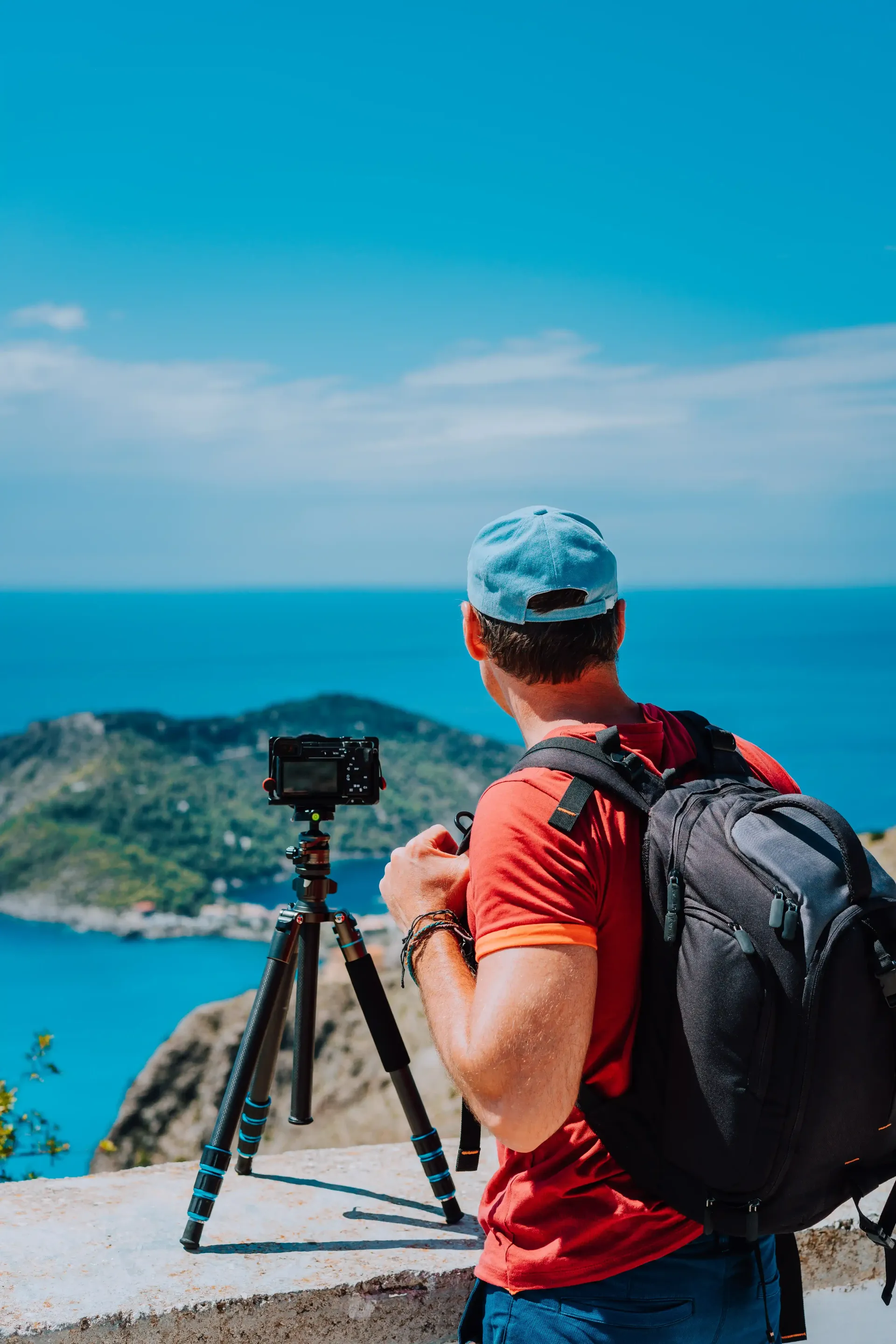 A man is taking a picture of the ocean with a camera on a tripod.