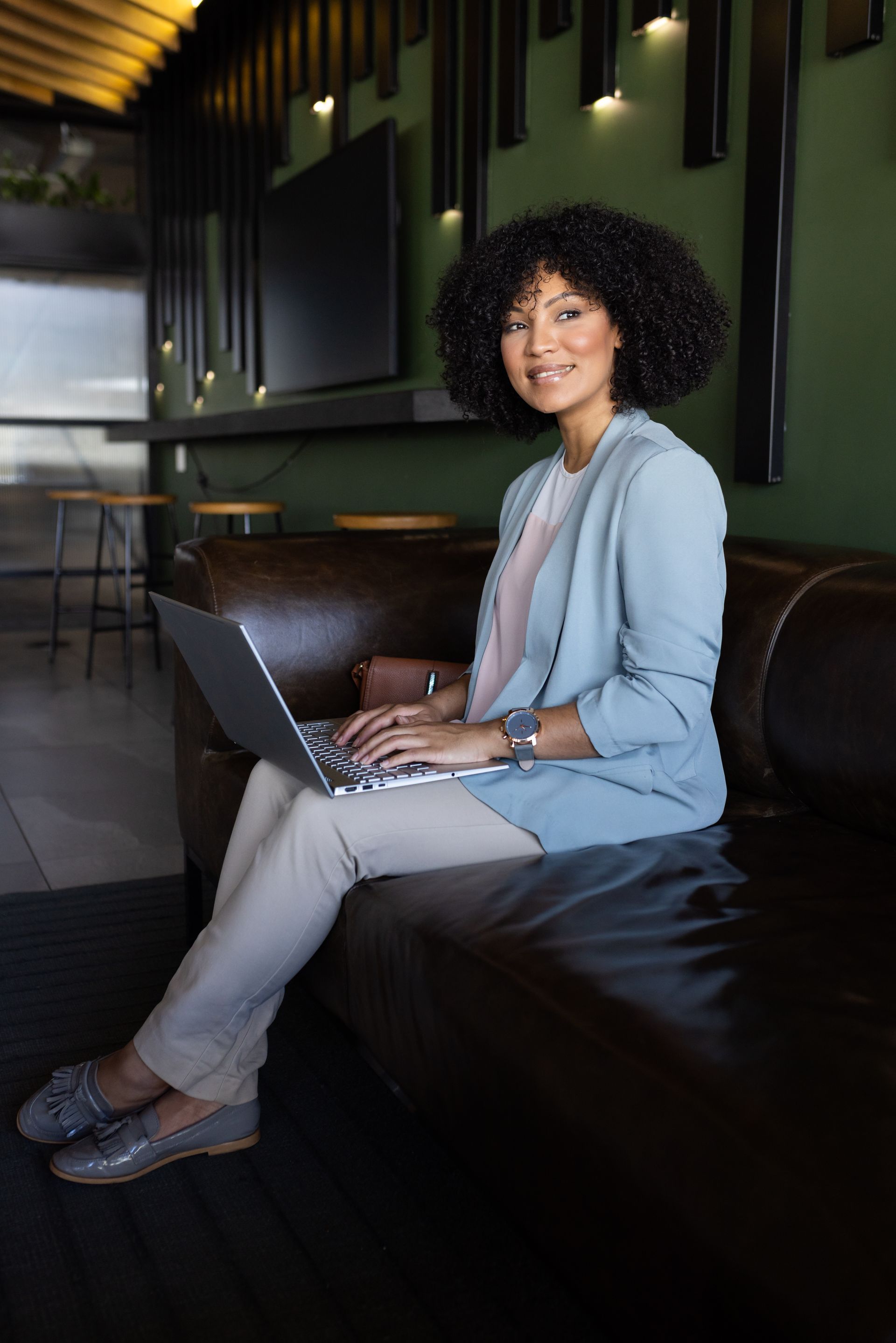 A woman is sitting on a couch using a laptop computer to increase revenue to her business through blogging.