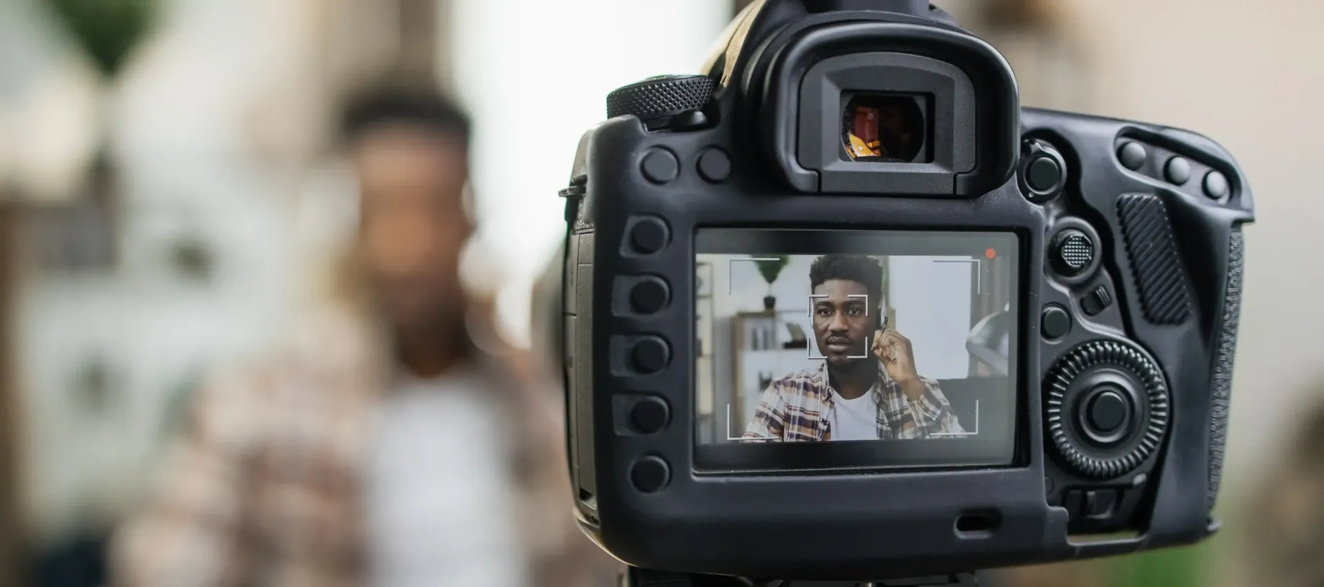 A camera is taking a picture of a man talking on a cell phone for content for his coaching business website.