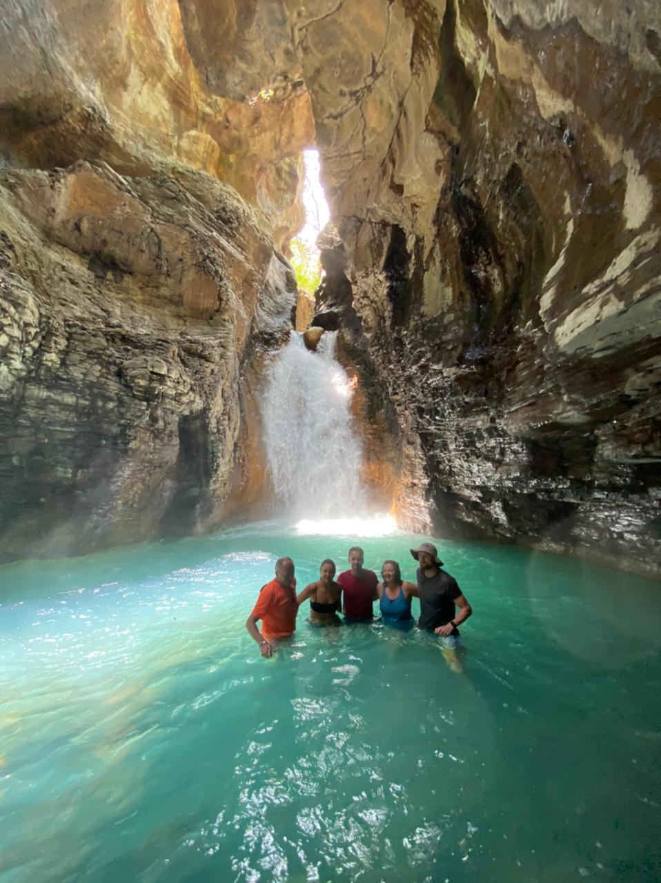 A group of people are standing in front of a waterfall in a cave.