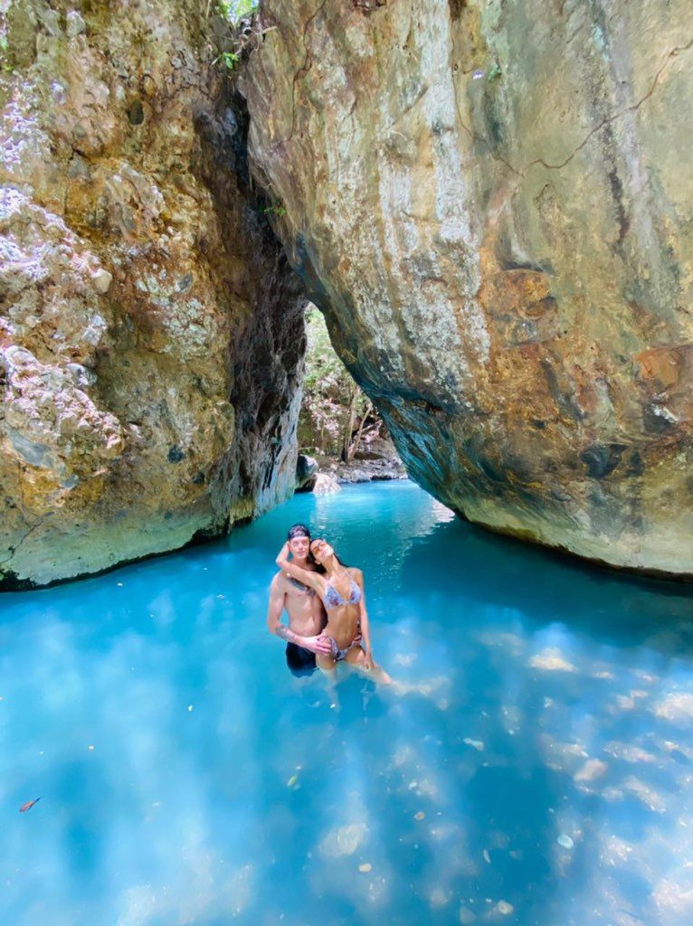 A couple is swimming in a river between two rocks.