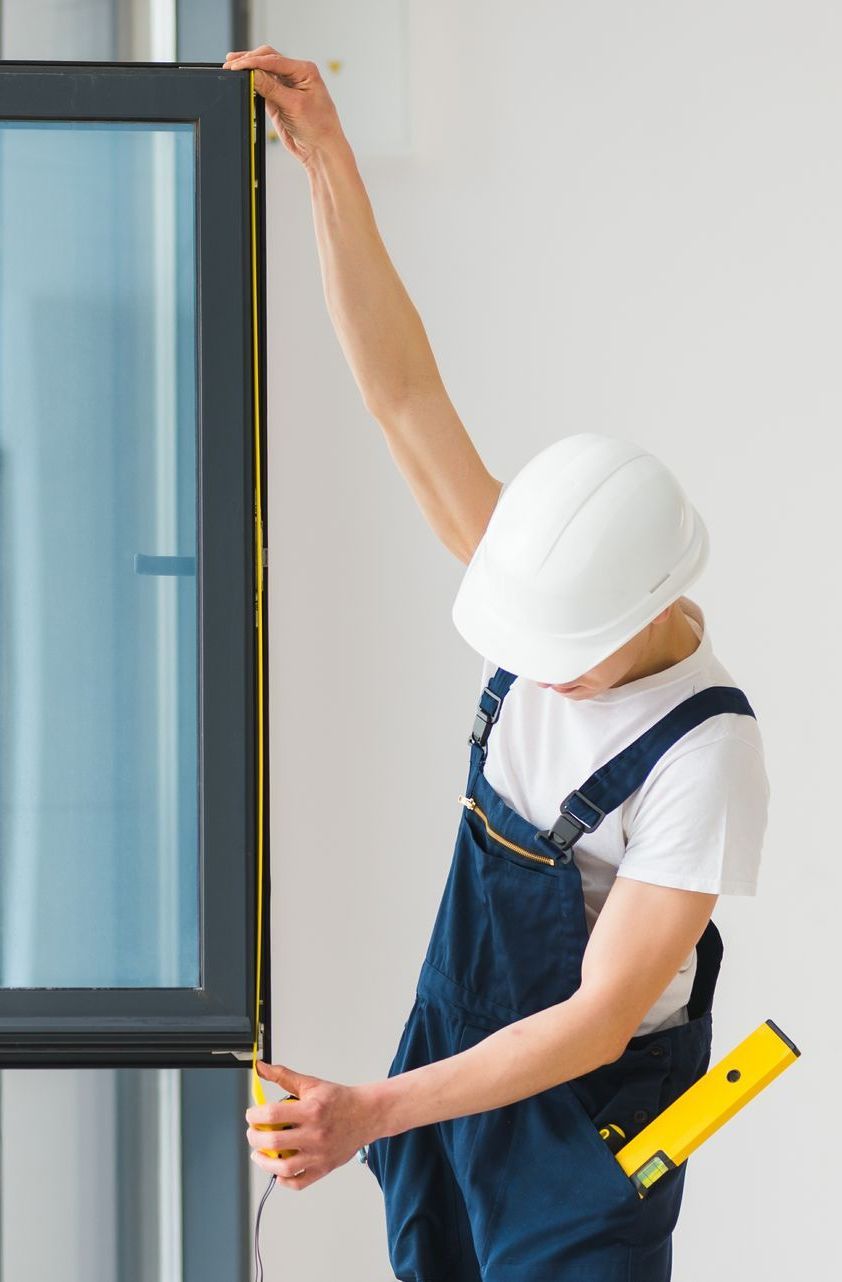 A man is measuring a window with a tape measure.