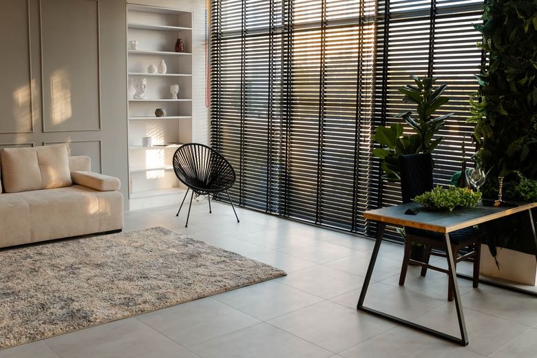 A living room with a couch , chair , desk and blinds.