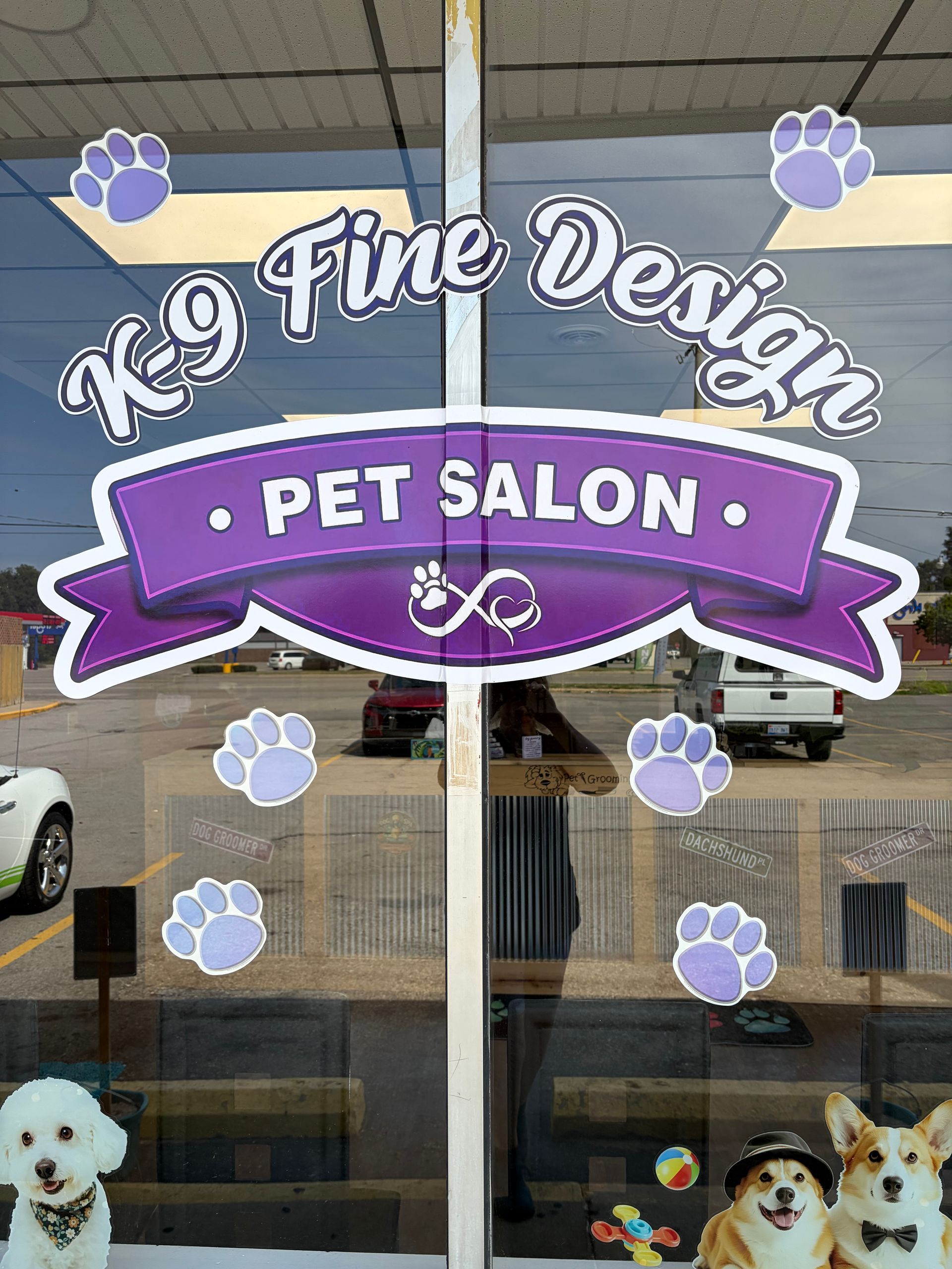 K9 Fine Design Pet Salon window sign with purple banner, paw prints, and dog photos inside the storefront