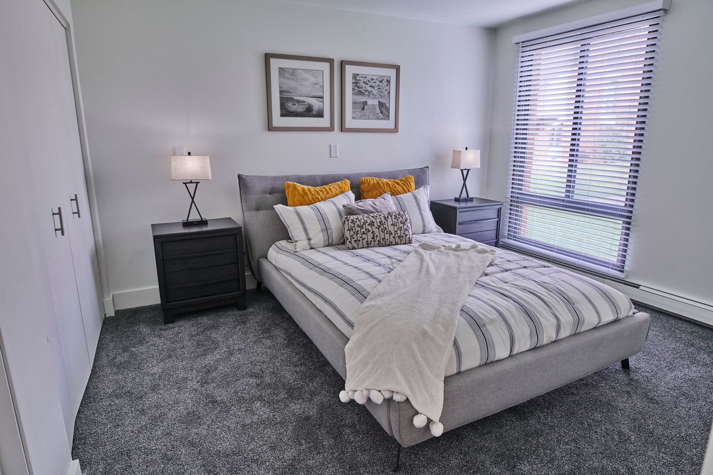 A bedroom with a large bed , nightstands , lamps and a window.