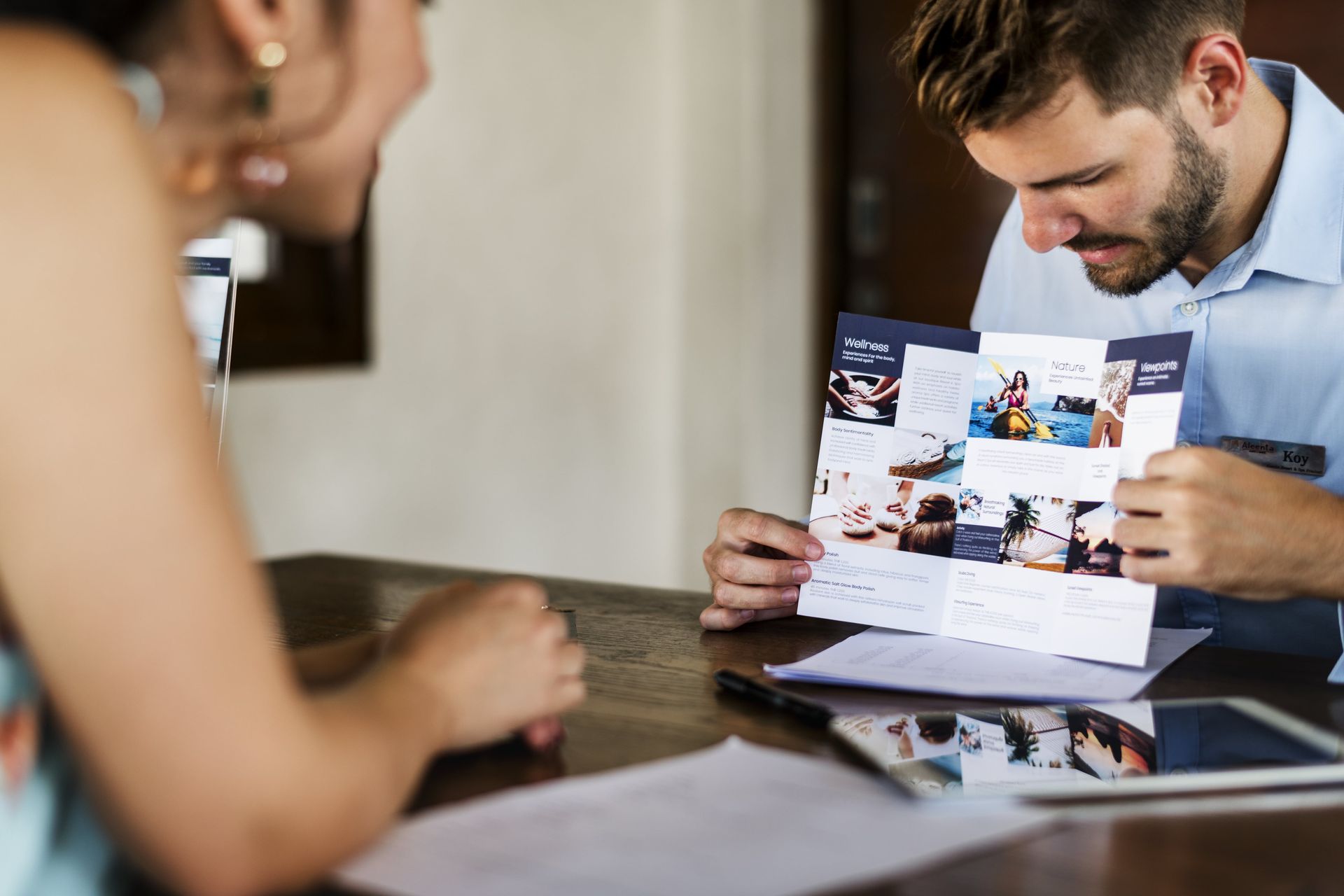 Reviewing a printed brochure with a staff member, showing in person leaflet marketing engagement