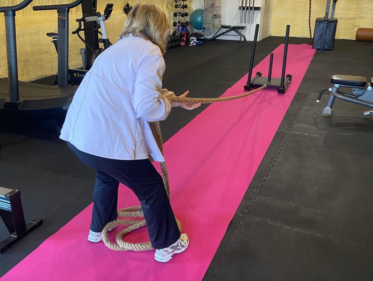 A woman is pulling a rope in a gym.