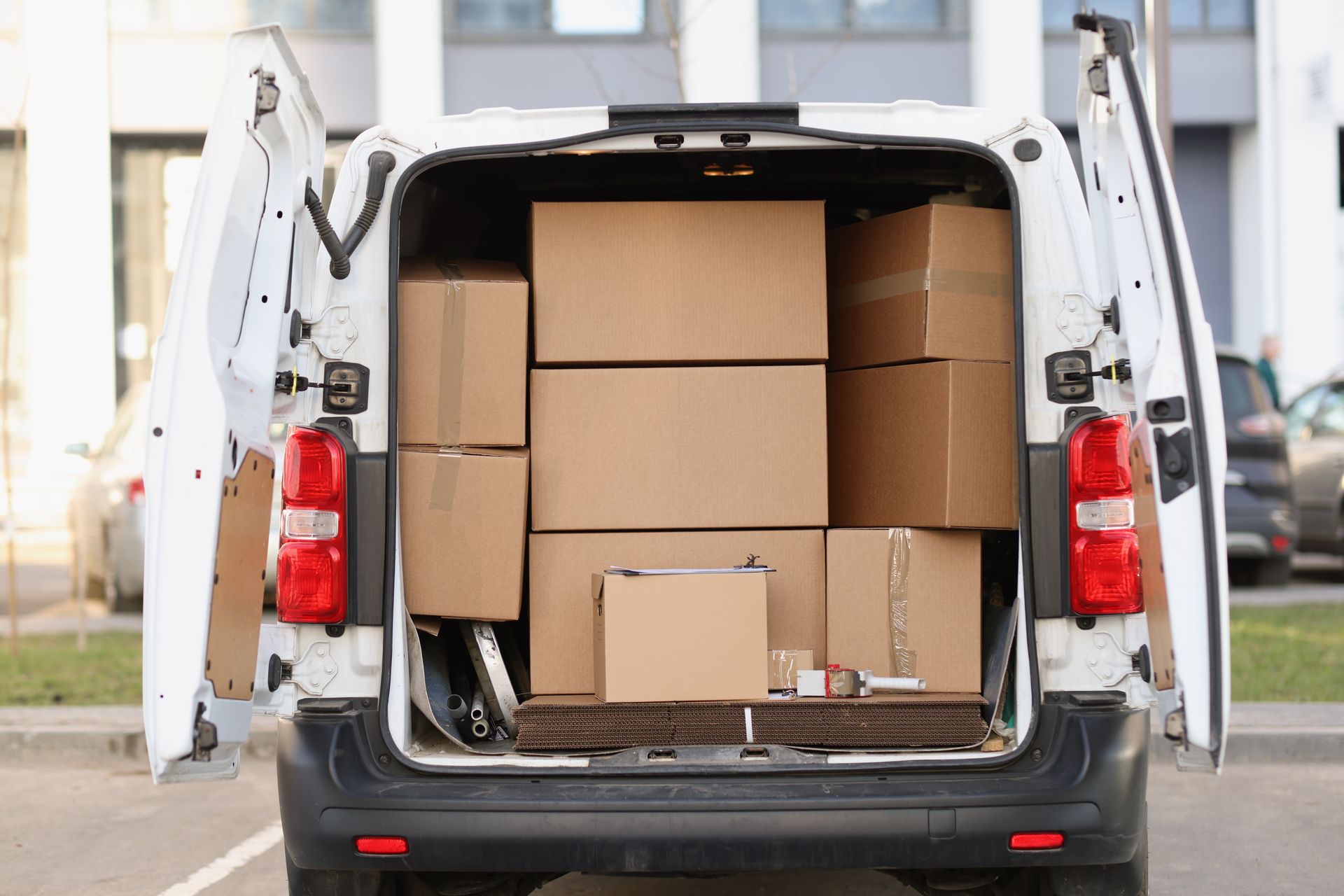 White van open, packed with stacked cardboard boxes, parked outdoors.