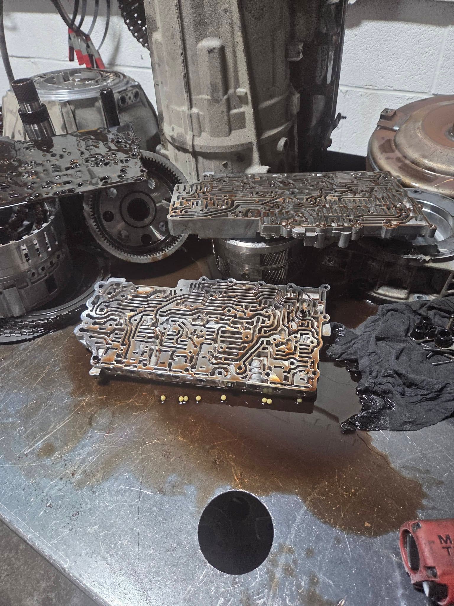 Close-up of a greasy metal engine part with exposed gears and oil on a workbench
