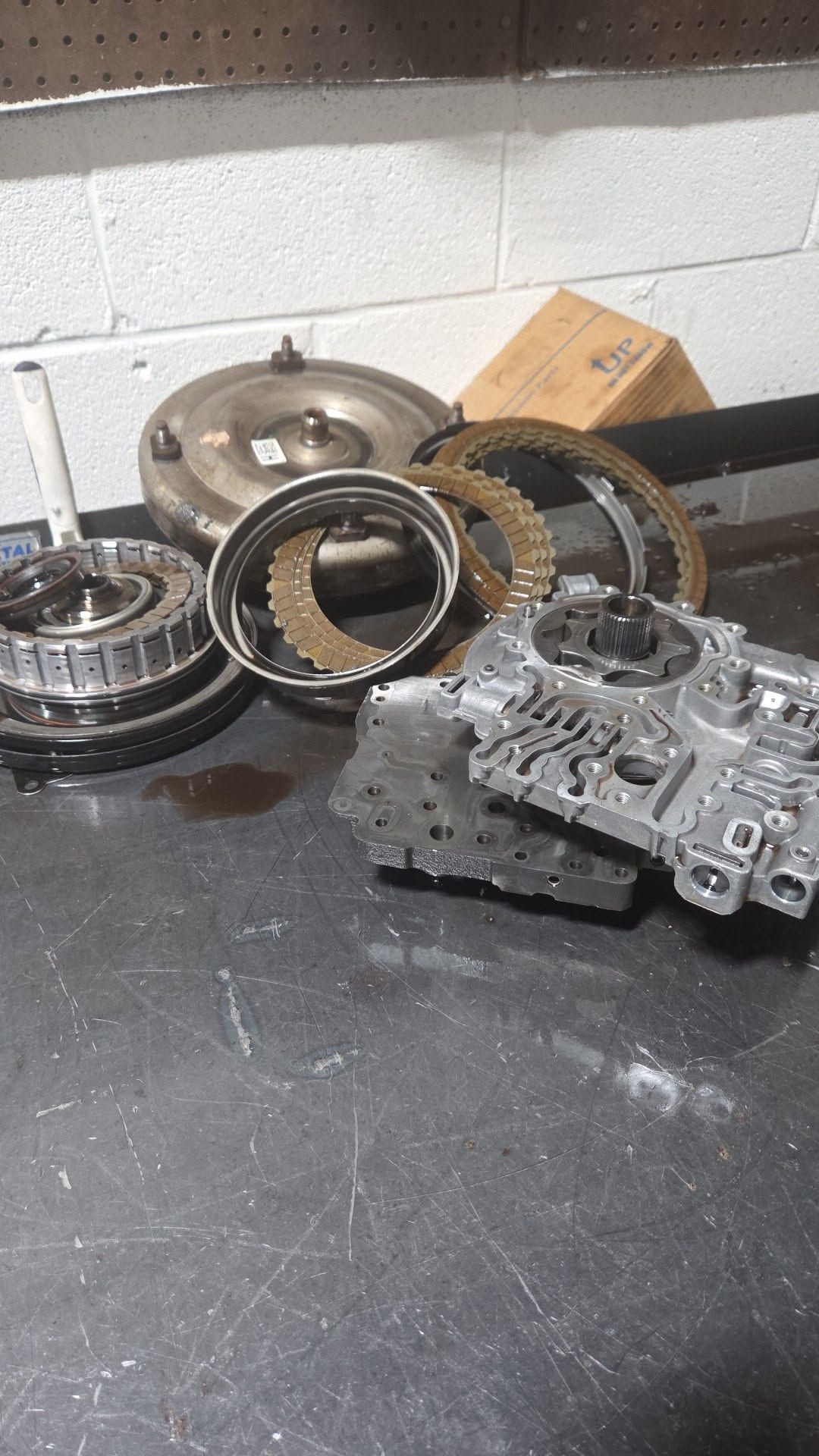 Assorted metal car transmission parts on a workbench in a garage workshop.