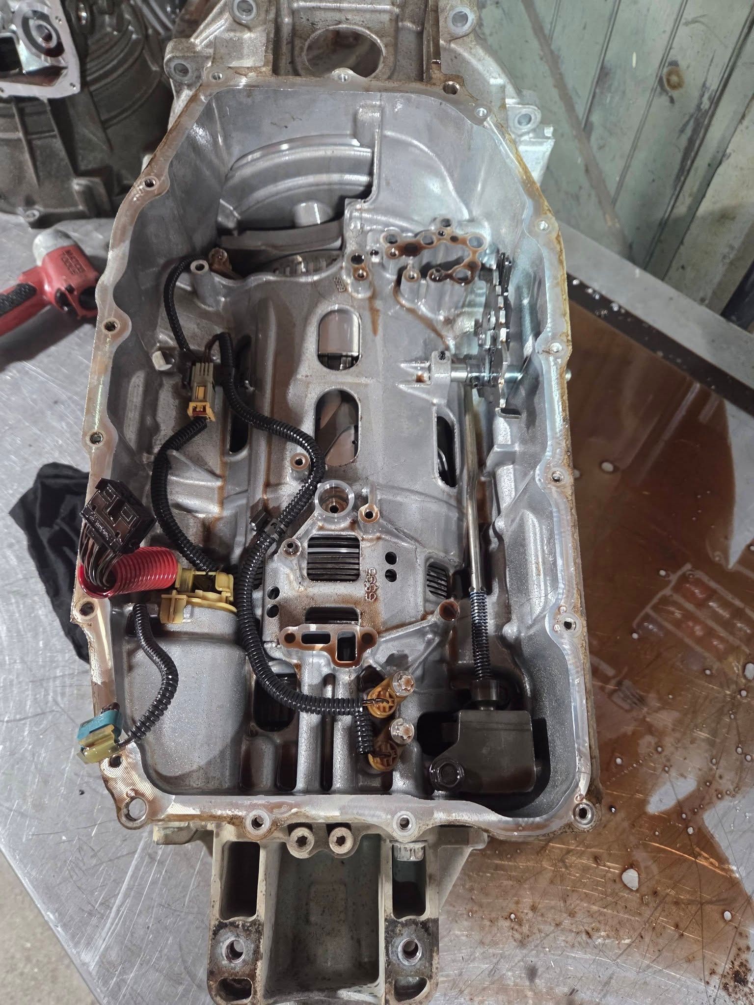 Open car transmission housing with exposed gears and wiring in a workshop