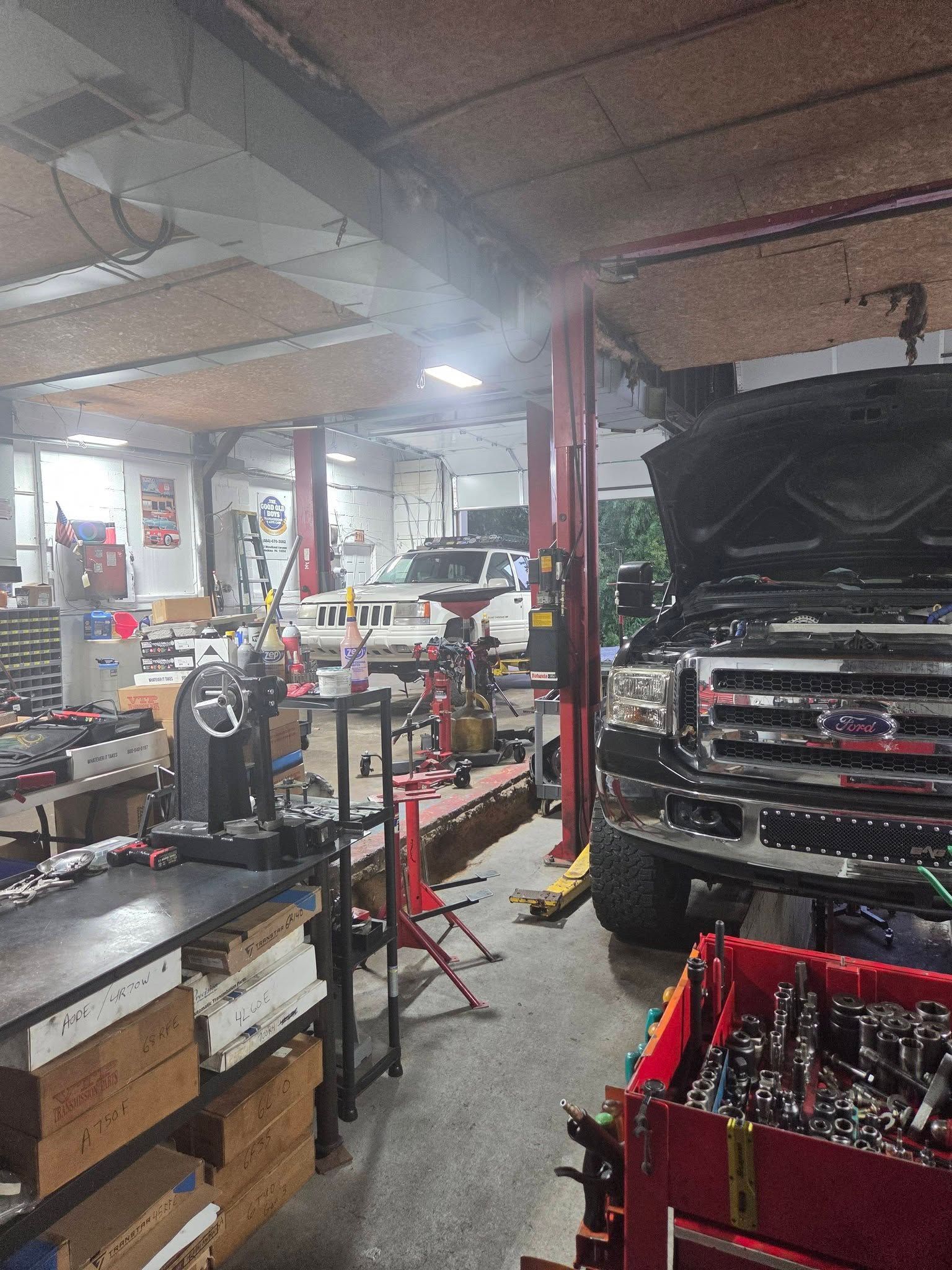 Auto repair shop with a black car on a lift, tools, and equipment in a cluttered garage