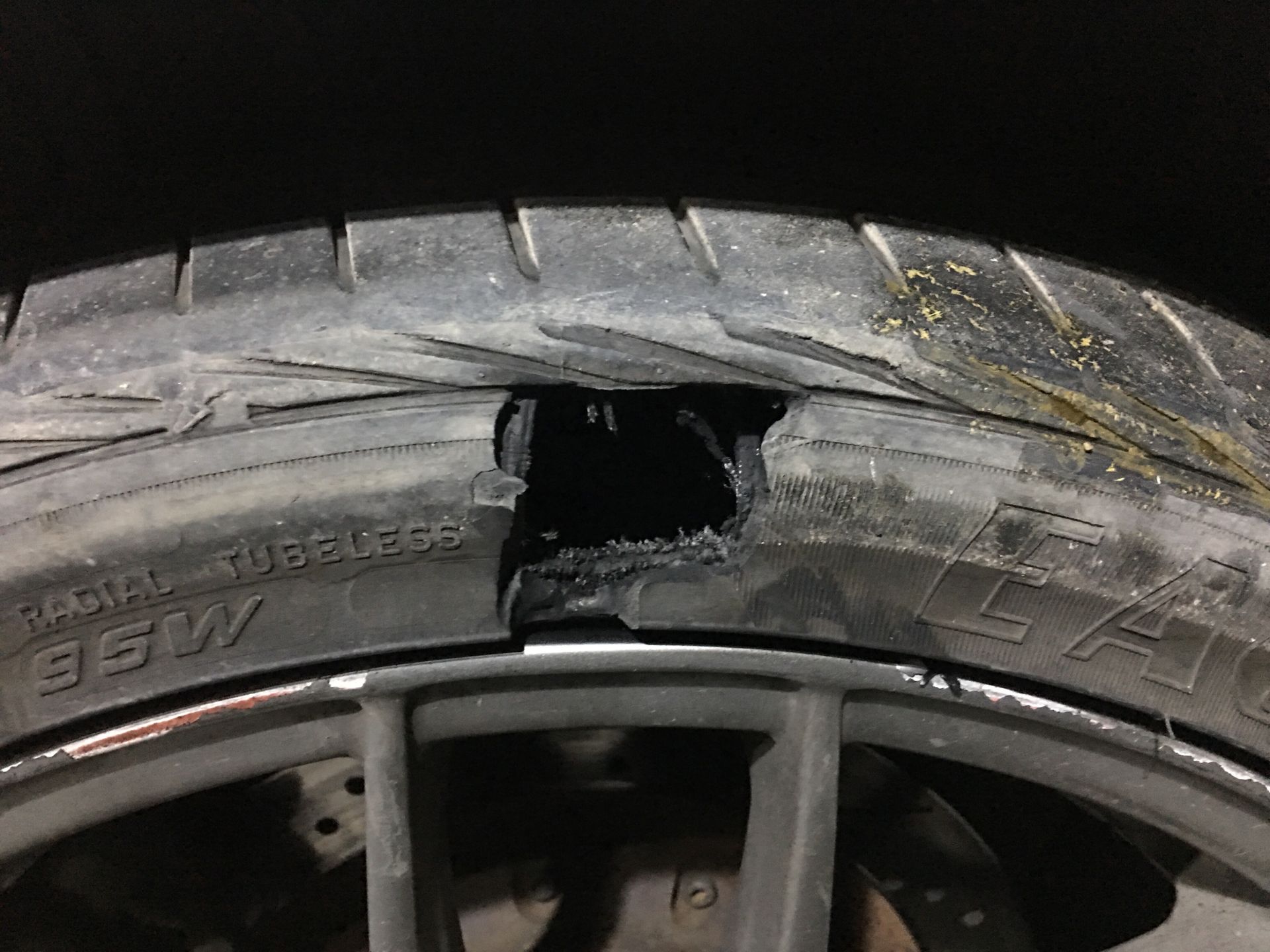 Damaged car tire after a tire blowout showing a large sidewall tear and rim damage