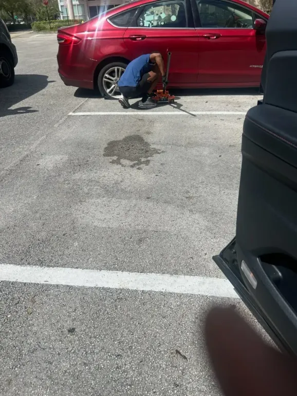 Technician using a floor jack while changing a sedan tire
