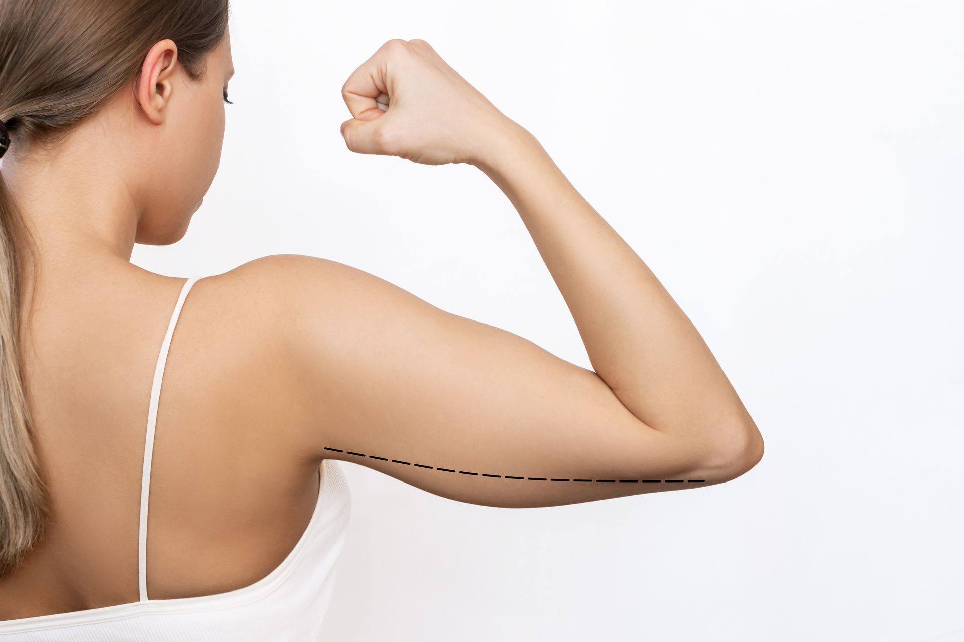 Woman flexing arm with dashed line marking upper arm on a white background