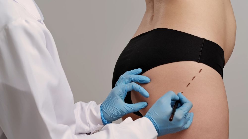 Gloved technician using a handheld device on a client’s back during a spa or skin treatment