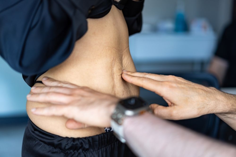 Therapist using a handheld device on a person’s lower back during a treatment session