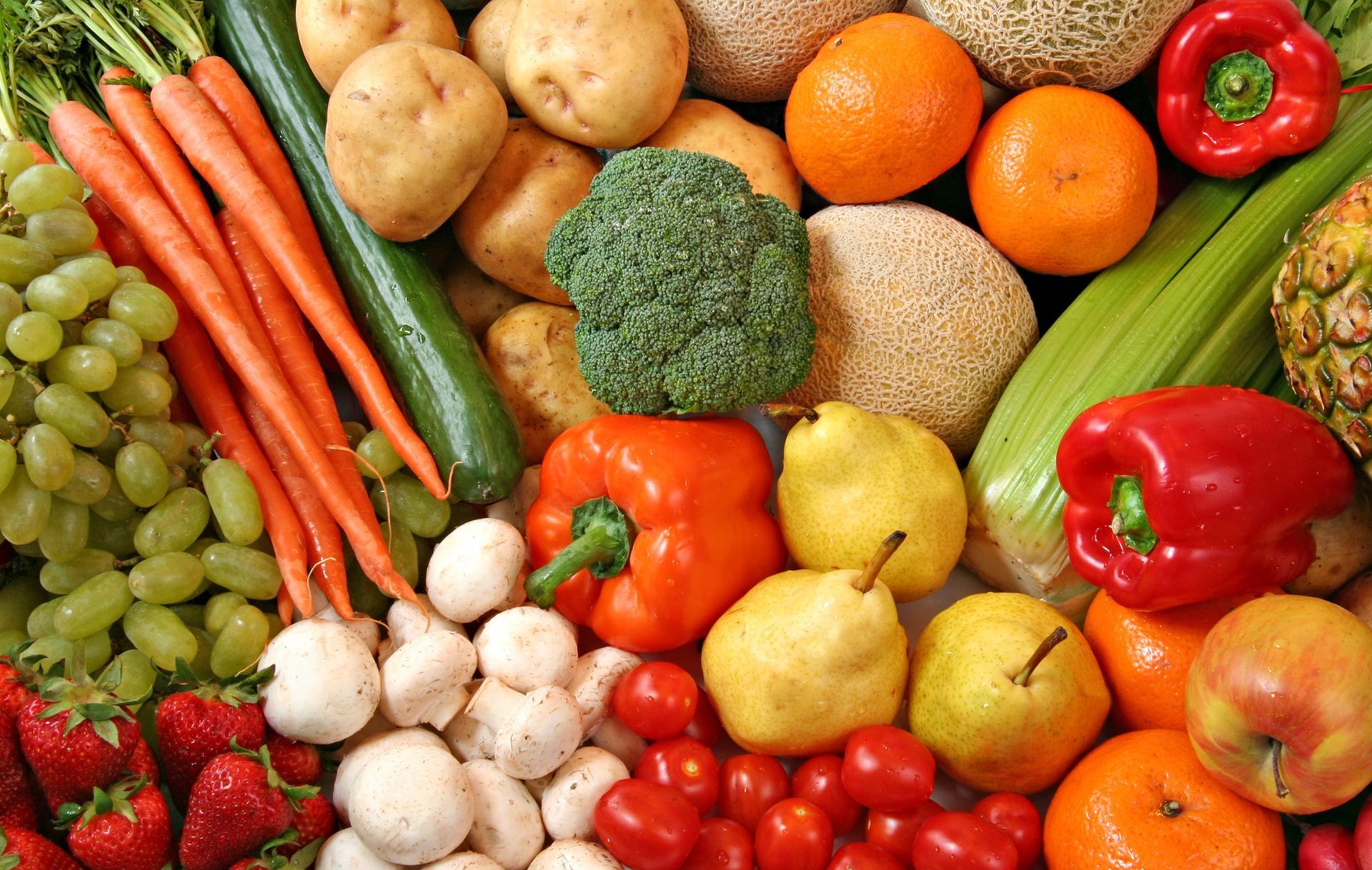 Assortimento di frutta e verdura fresca, tra cui uva, carote, arance e peperoni.
