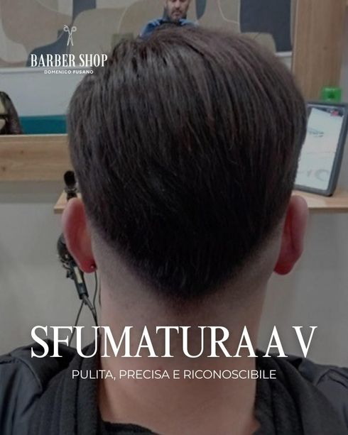 Vista posteriore di un taglio di capelli corto con sfumatura a V, riflessa nello specchio di un barbiere.