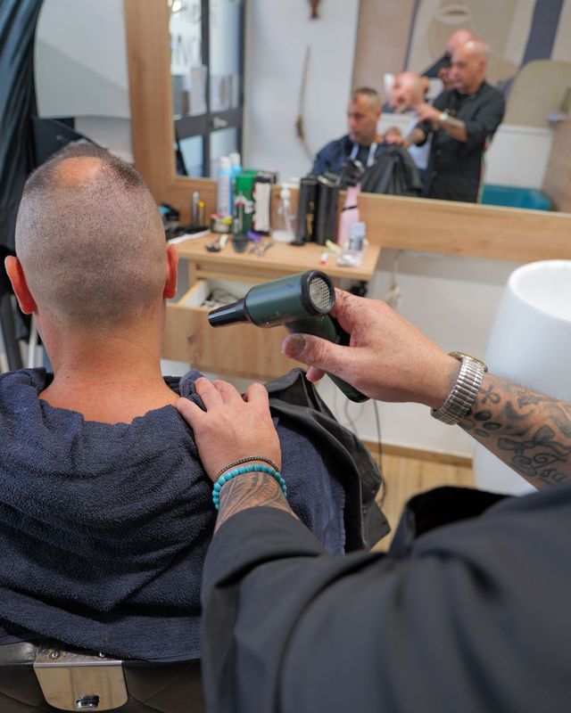 Un barbiere rade il viso di un cliente con un rasoio a mano libera in una classica barberia.