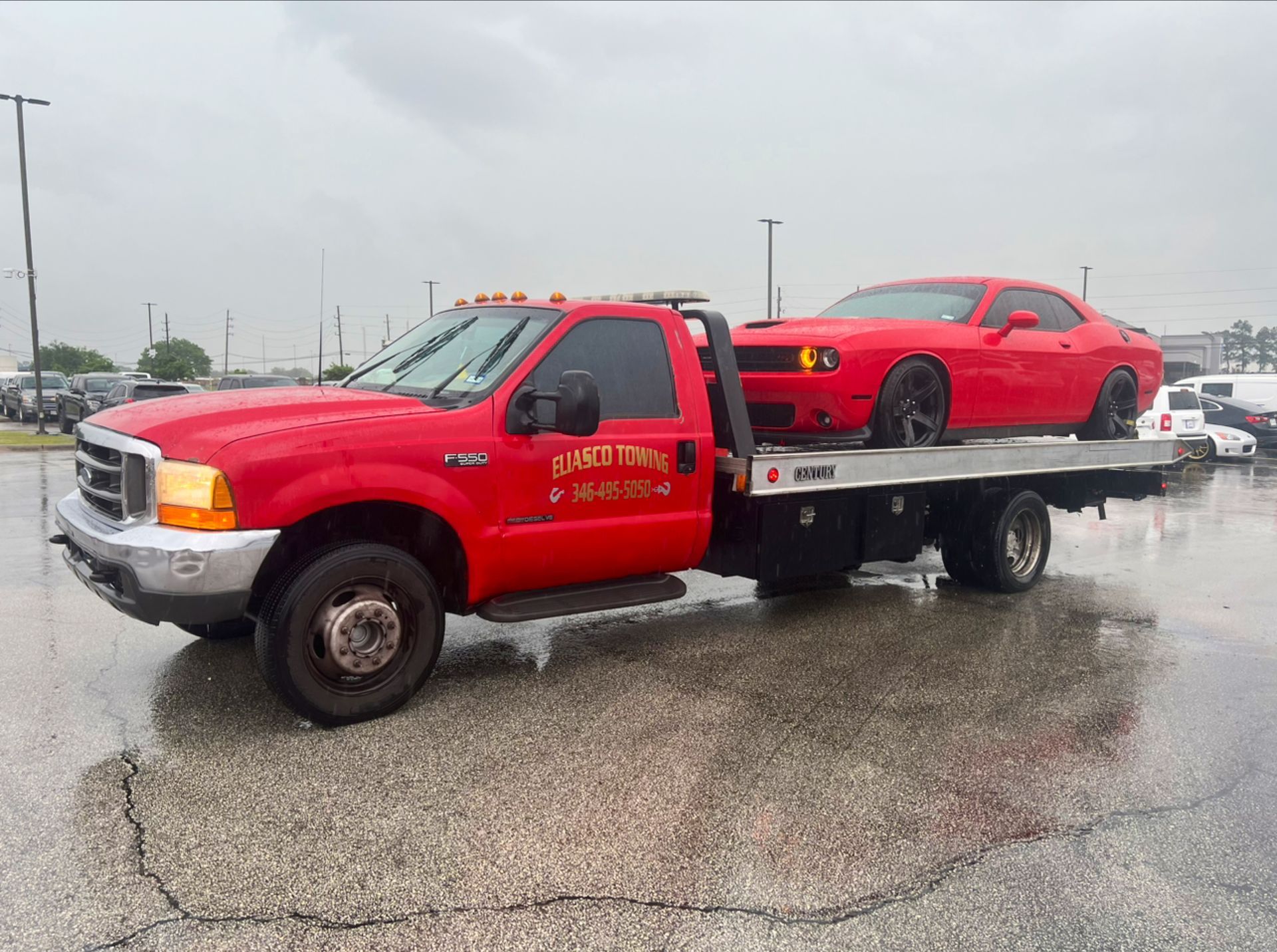 Red tow truck carrying a red sports car on a rainy road