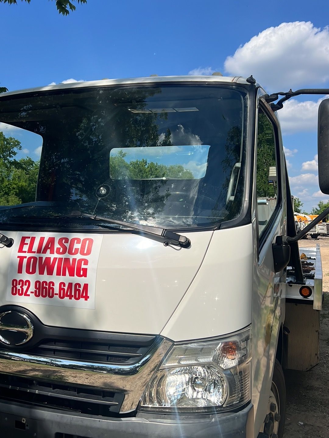 White ELASCO TOWING truck with red lettering parked outdoors under a blue sky