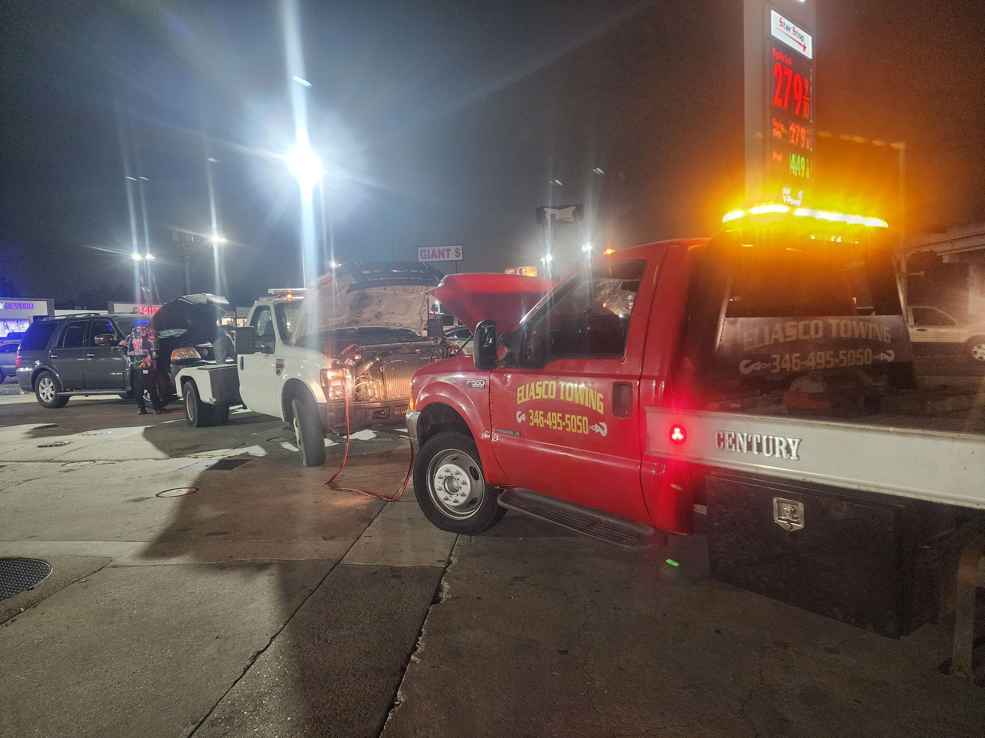 Tow trucks with flashing lights at a roadside scene at night