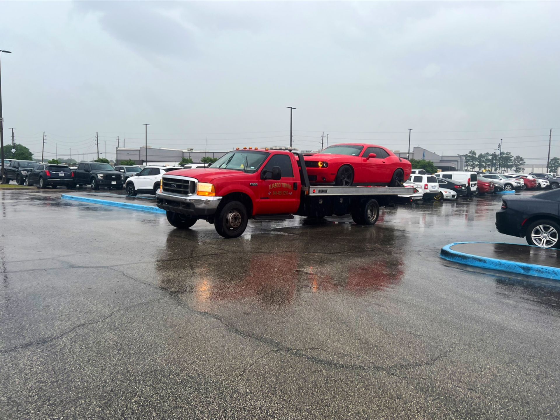Red pickup truck carrying a red ATV in a wet parking lot on a rainy day
