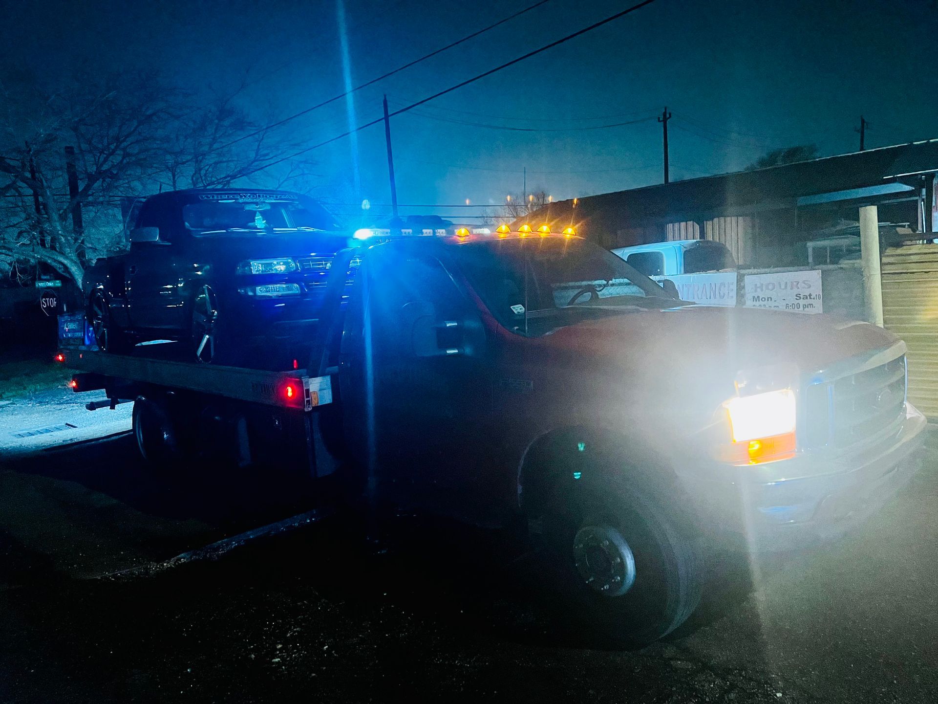 Tow truck with flashing blue lights at night on a dark street