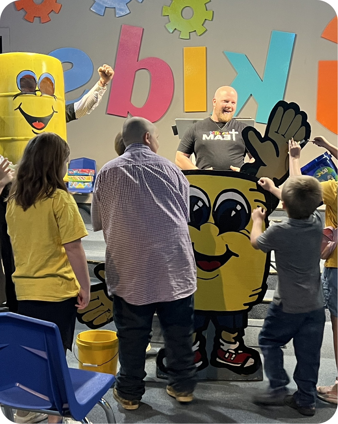 Children gather around colorful M&M characters and letters at a lively indoor event.
