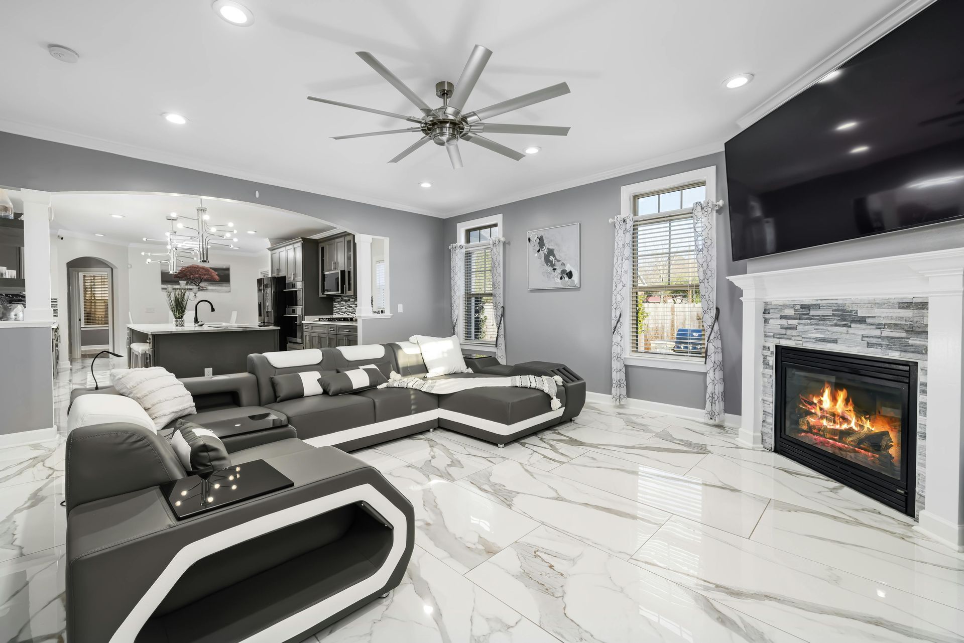 A living room with a couch , fireplace , television and ceiling fan.