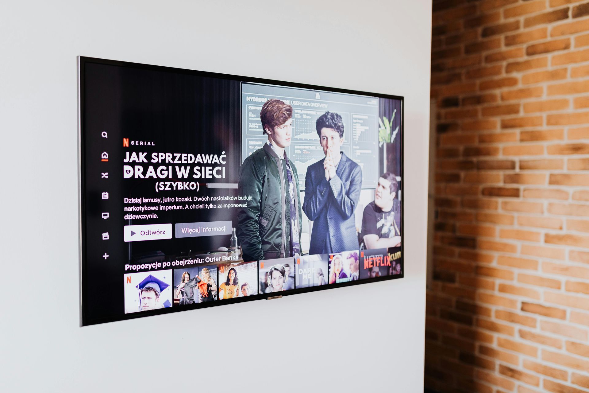 A flat screen tv is hanging on a brick wall.