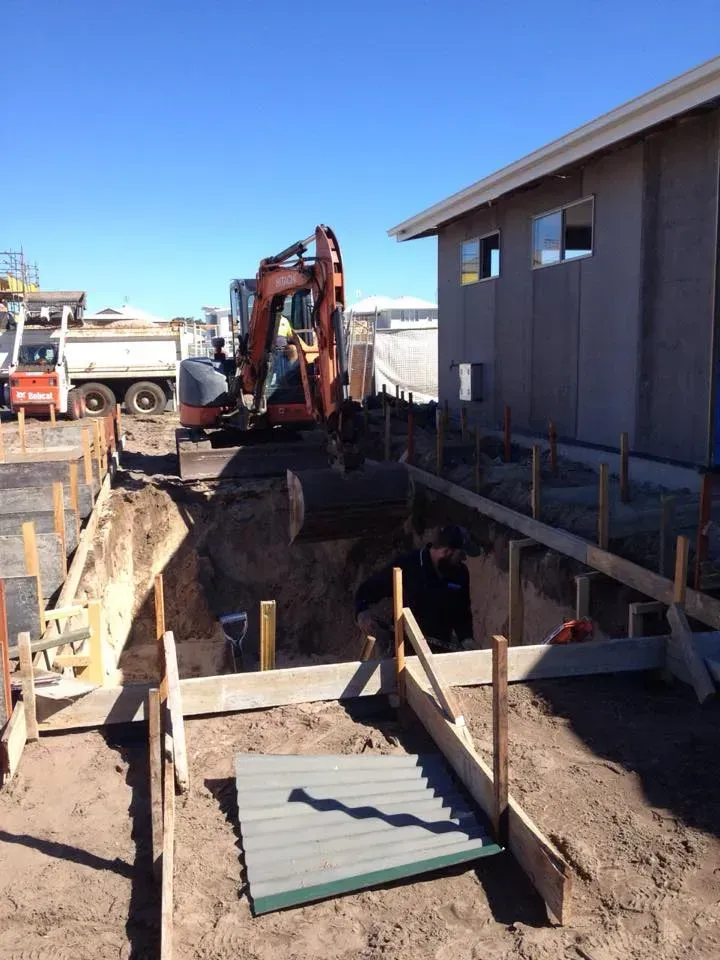 Construction Site With Excavator Digging A Trench Beside A Building And Truck In The Background — Border Rockwalls in Stotts Creek, NSW