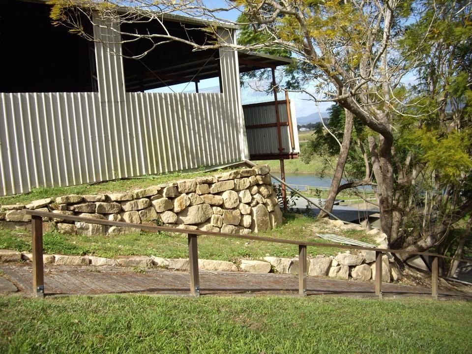 Stone Retaining Wall Beside a Corrugated Shed and Tree — Border Rockwalls in Stotts Creek, NSW