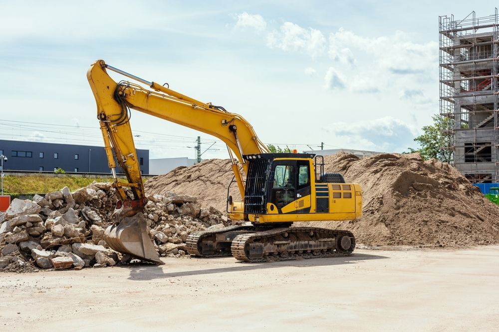 Yellow Excavator Clearing Rubble At A Construction Site Beside A Scaffolded Building — Border Rockwalls in Murwillumbah, NSW