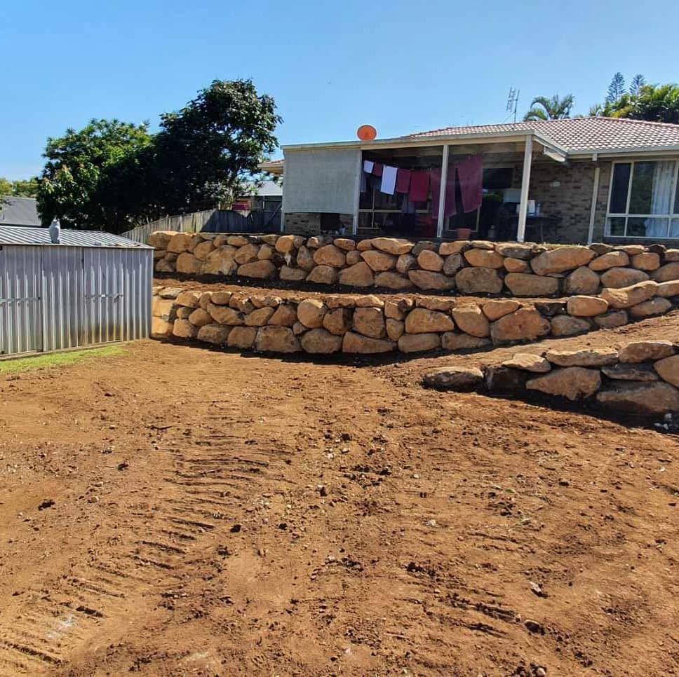 Dirt Yard With Stacked Stone Retaining Wall and a Small House — Border Rockwalls in Stotts Creek, NSW