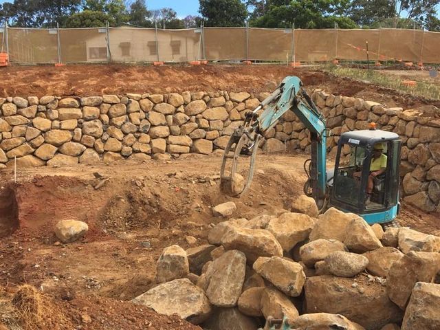 Excavator Moving Large Rocks at a Stone Retaining Wall — Border Rockwalls in Stotts Creek, NSW