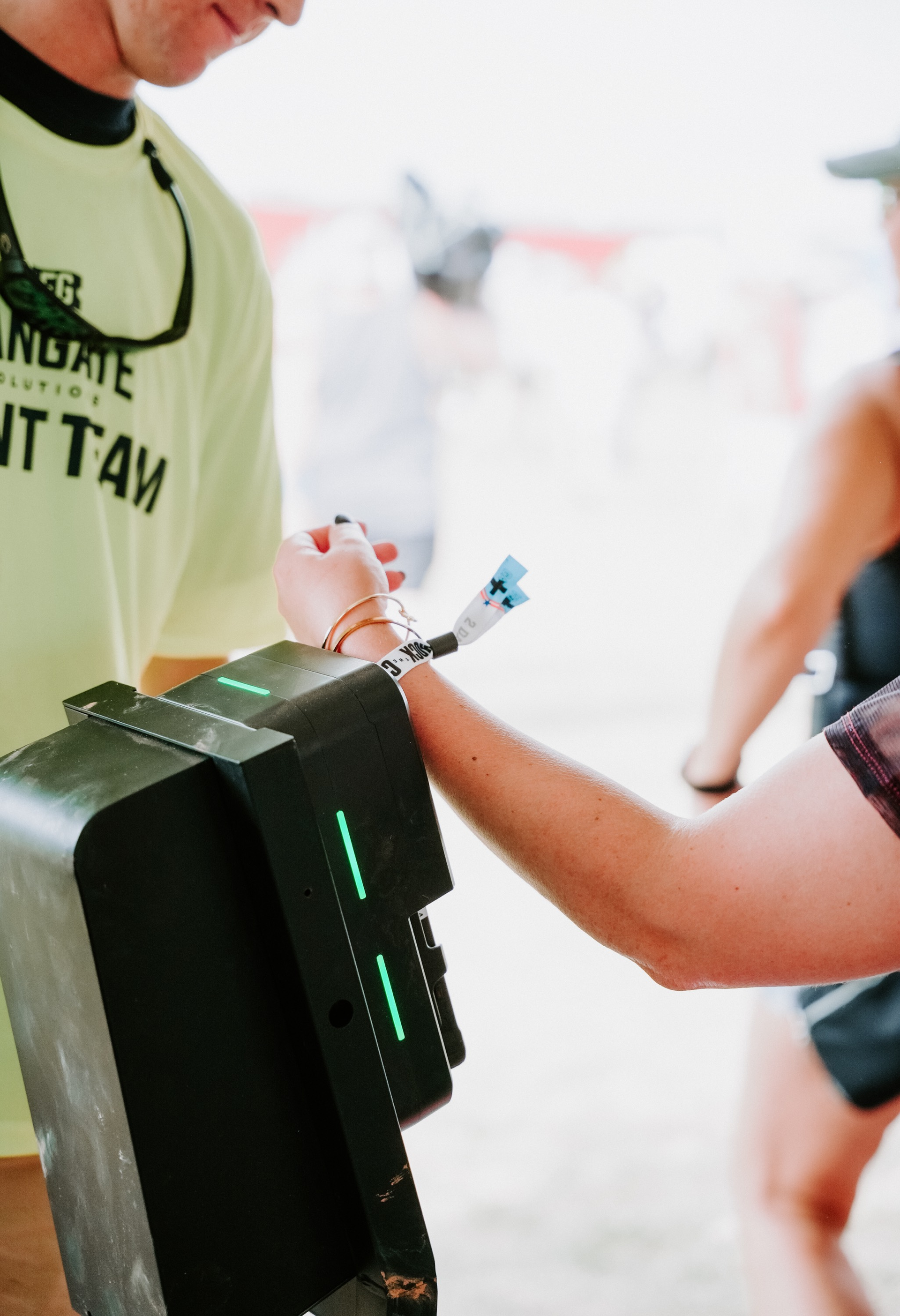 ticketing team member assisting event concert attendee with scanning their event wristband