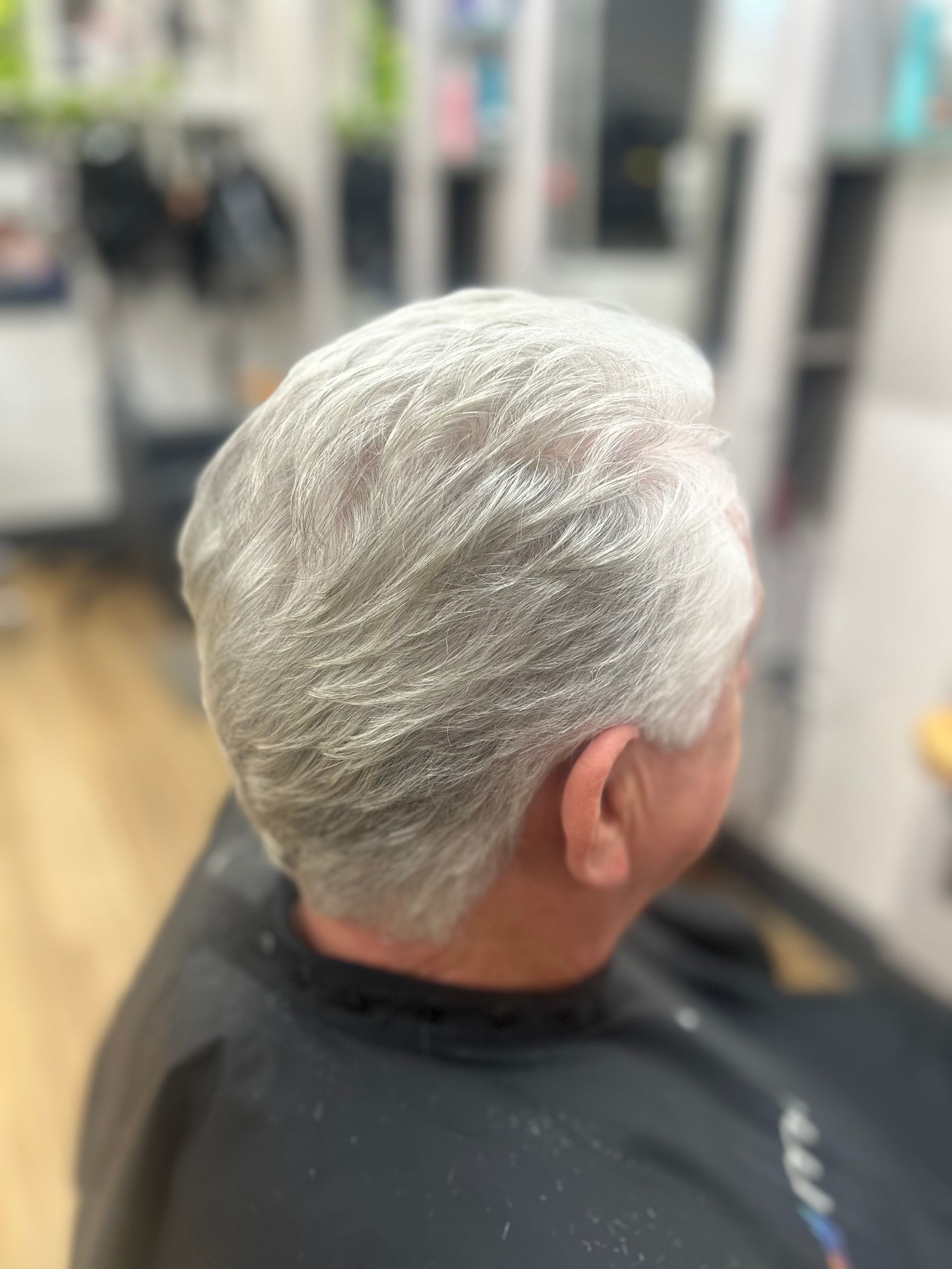 Close-up of short silver hair on a person seated in a salon chair