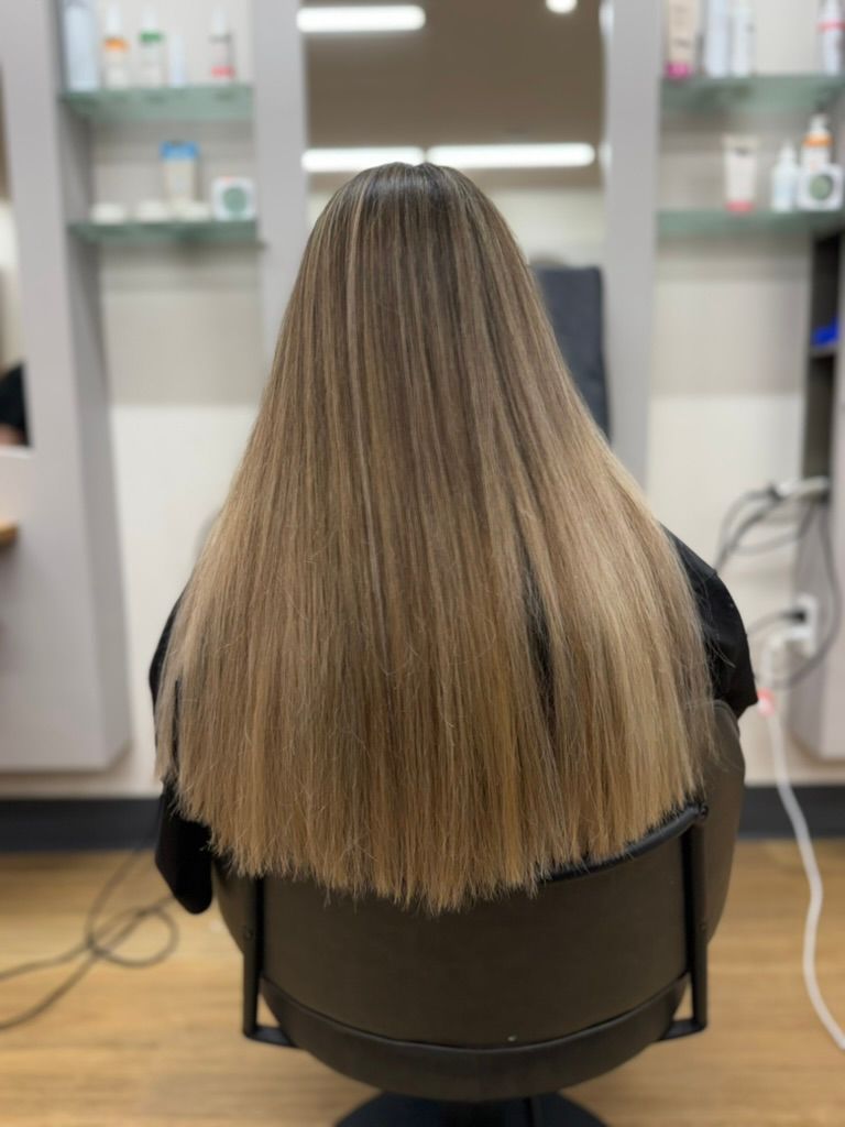 Woman with long wavy blonde hair standing in a bright salon, viewed from behind. — Hair to Impress In Lisarow, NSW