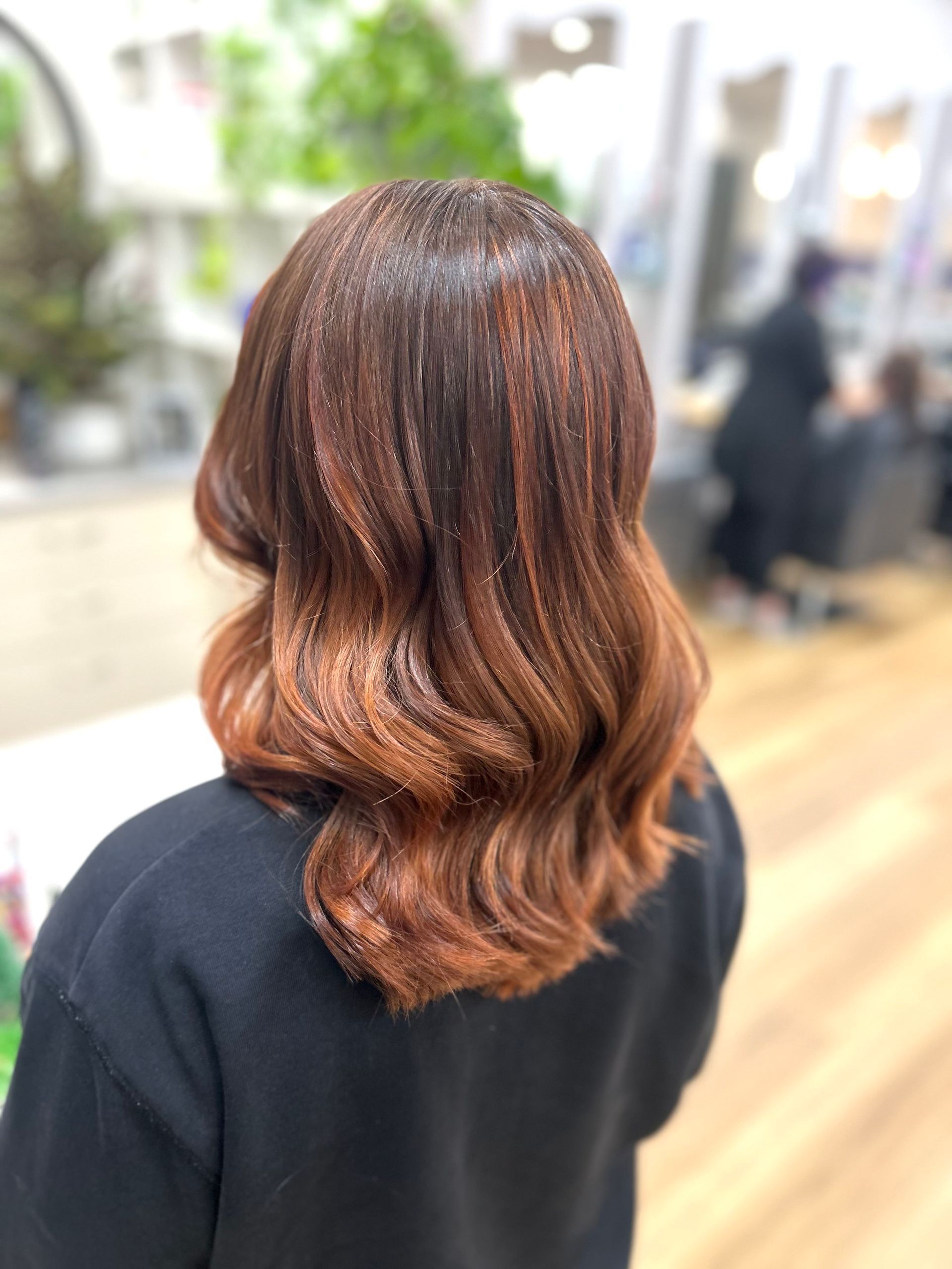 Rear view of wavy brown hair with auburn highlights in a salon setting