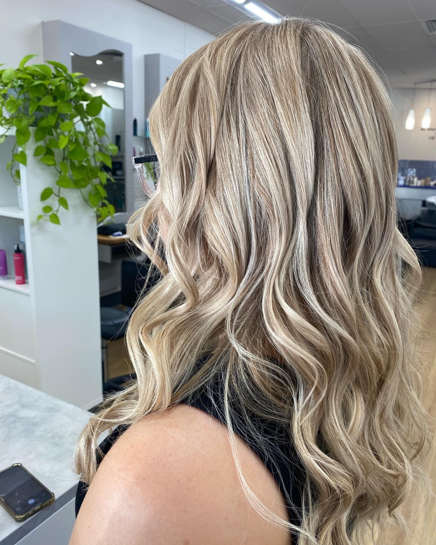 Long blonde wavy hair with dark roots, shown from the back in a salon setting — Hair to Impress In Lisarow, NSW