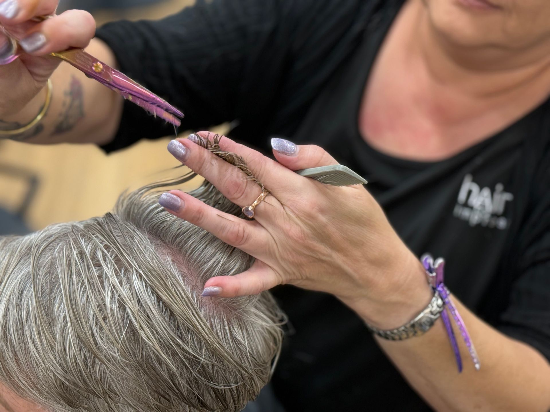 Stylist dyeing a client's gray hair with purple highlights in a salon — Hair to Impress In Lisarow, NSW