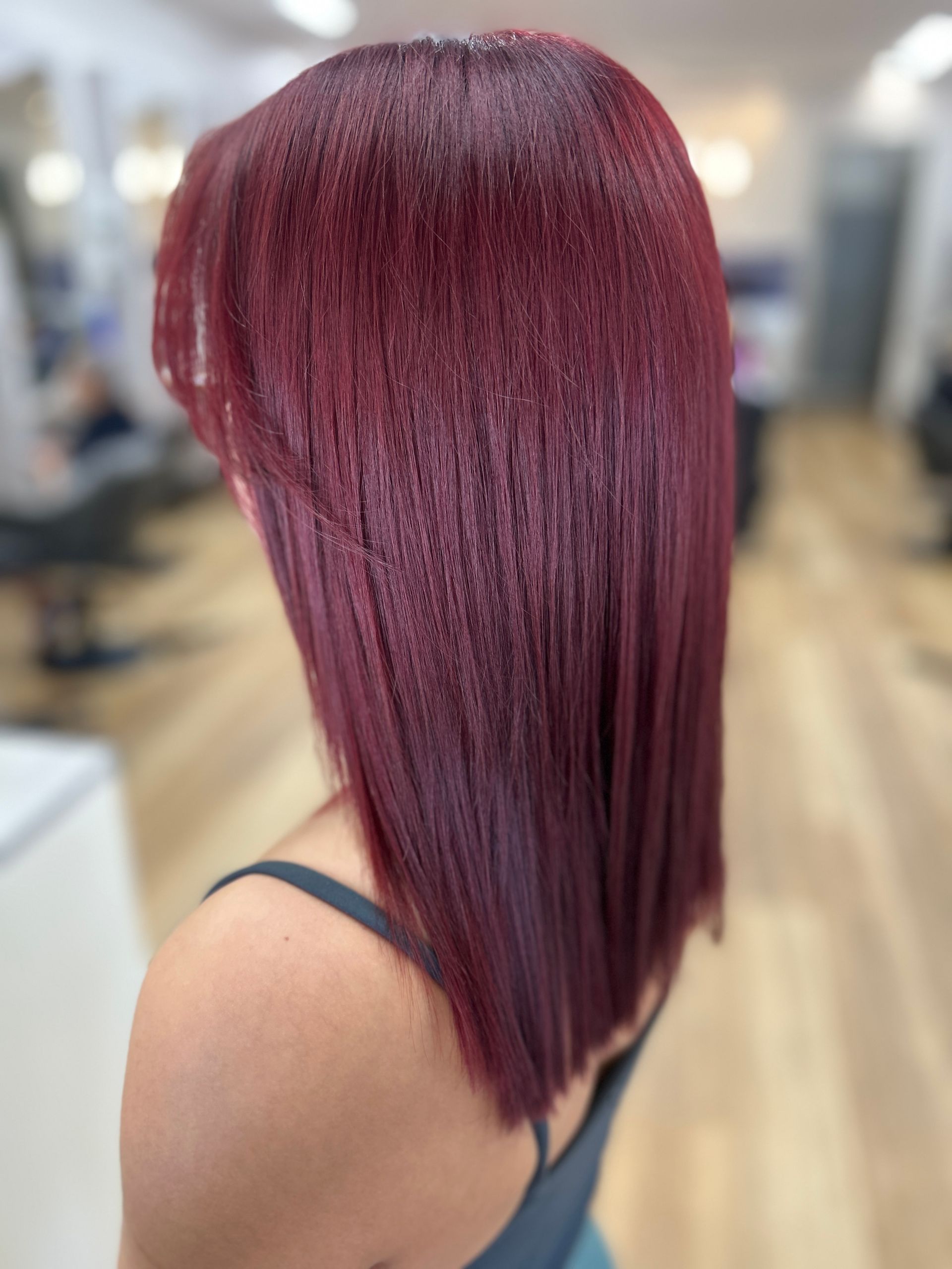 Side view of a sleek burgundy bob haircut in a salon setting