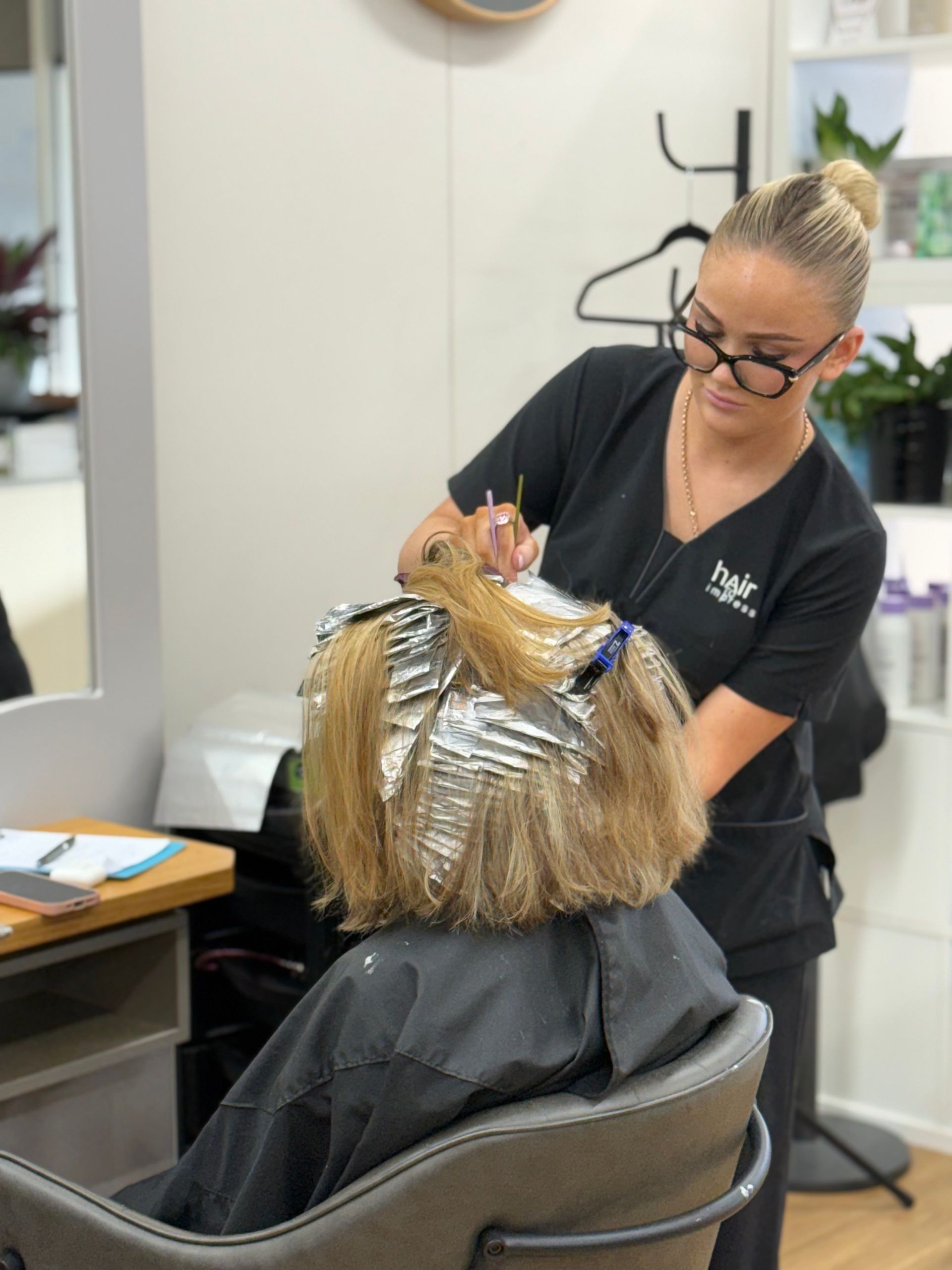 Stylist applying foil highlights to a client’s hair in a salon chair - Hair to Impress in Lisarow NSW