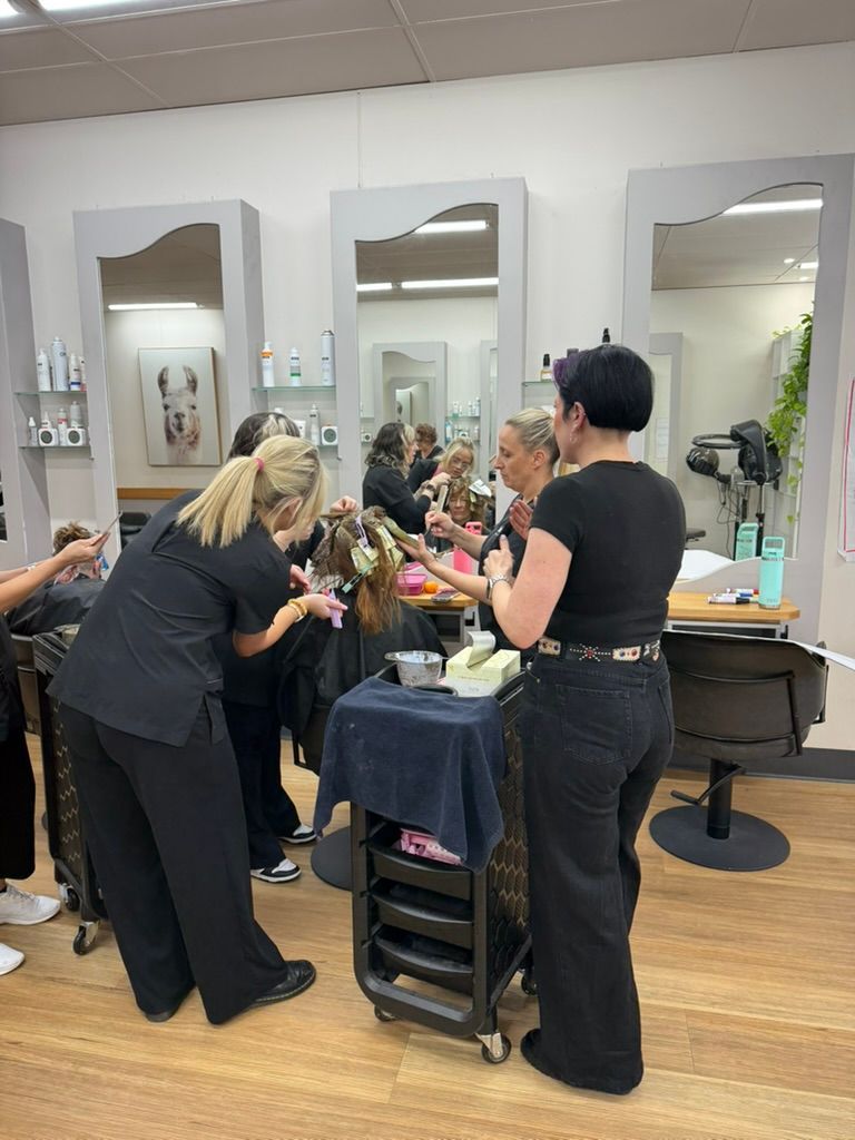 People gathered around a salon station, leaning in to talk and work among mirrors and chairs — Hair to Impress In Lisarow, NSW