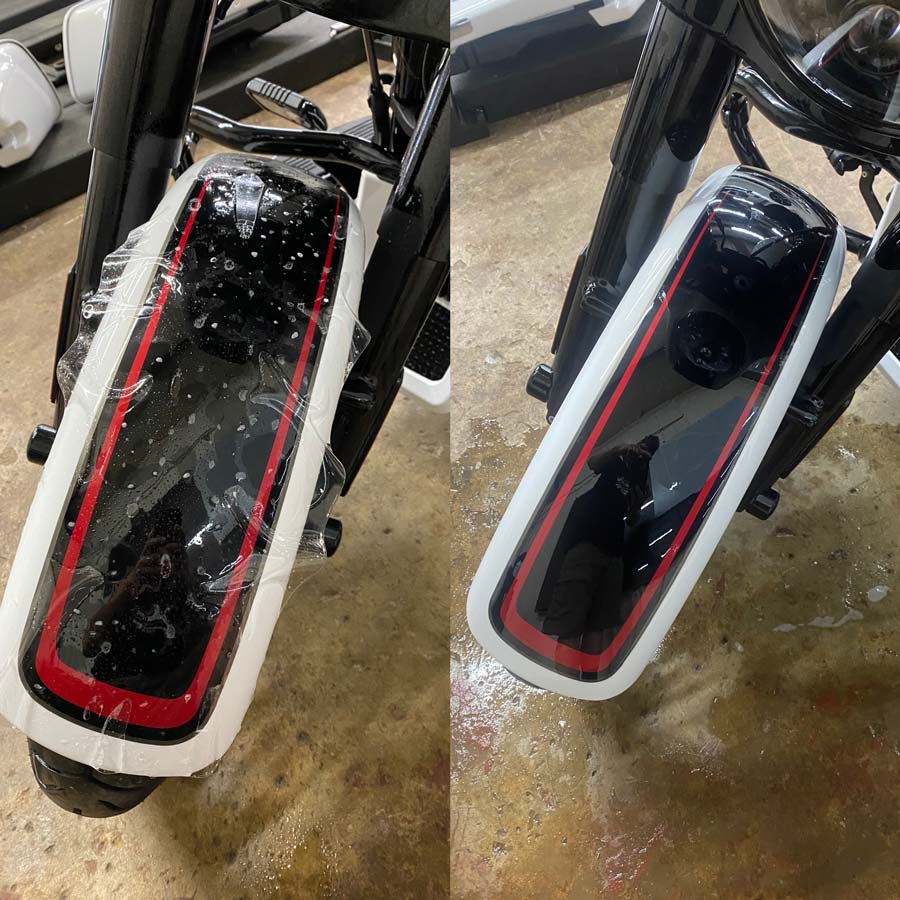 A motorcycle with a red and white stripe on the front is sitting on a concrete floor.