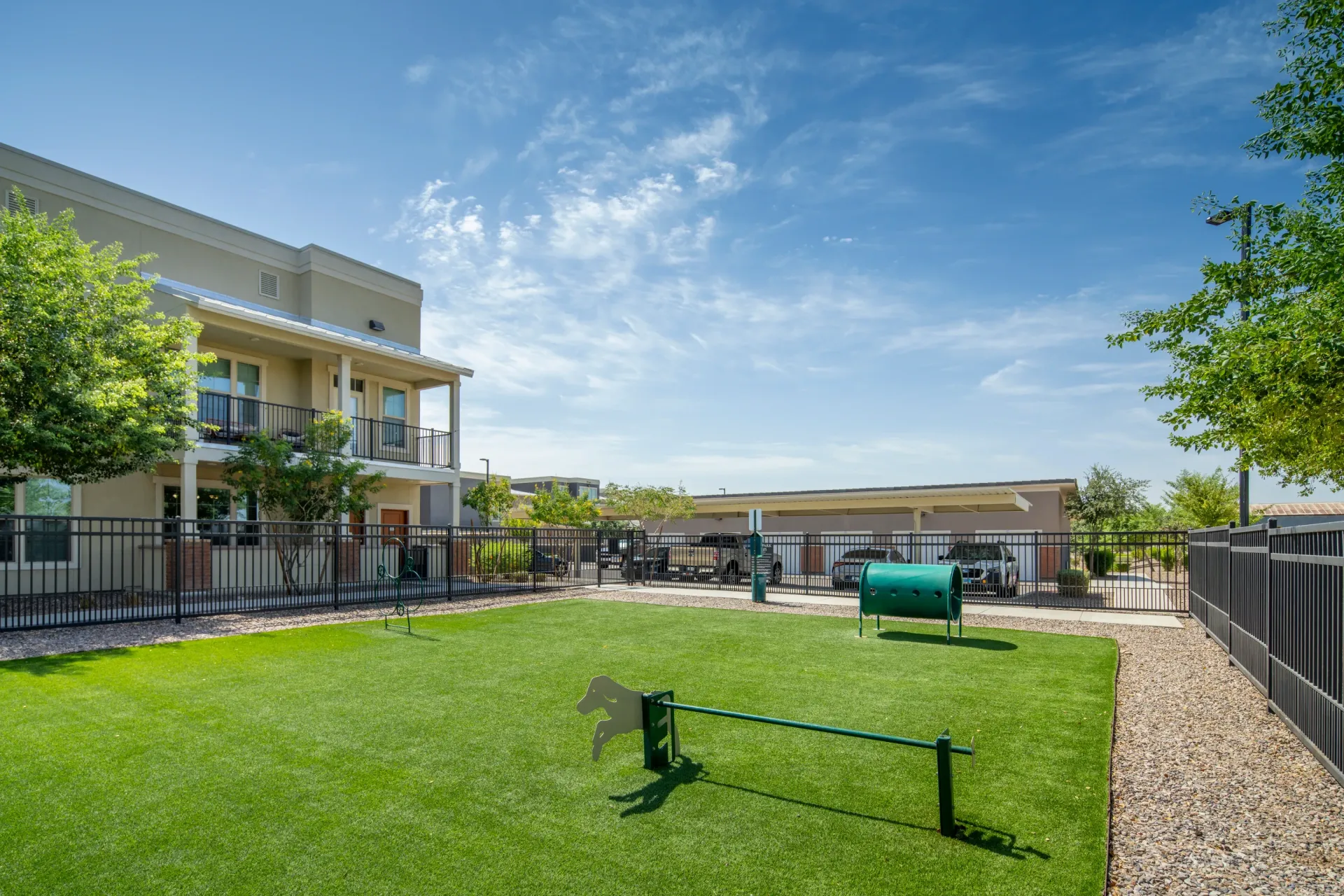 Apartment complex dog park with agility equipment and turf.